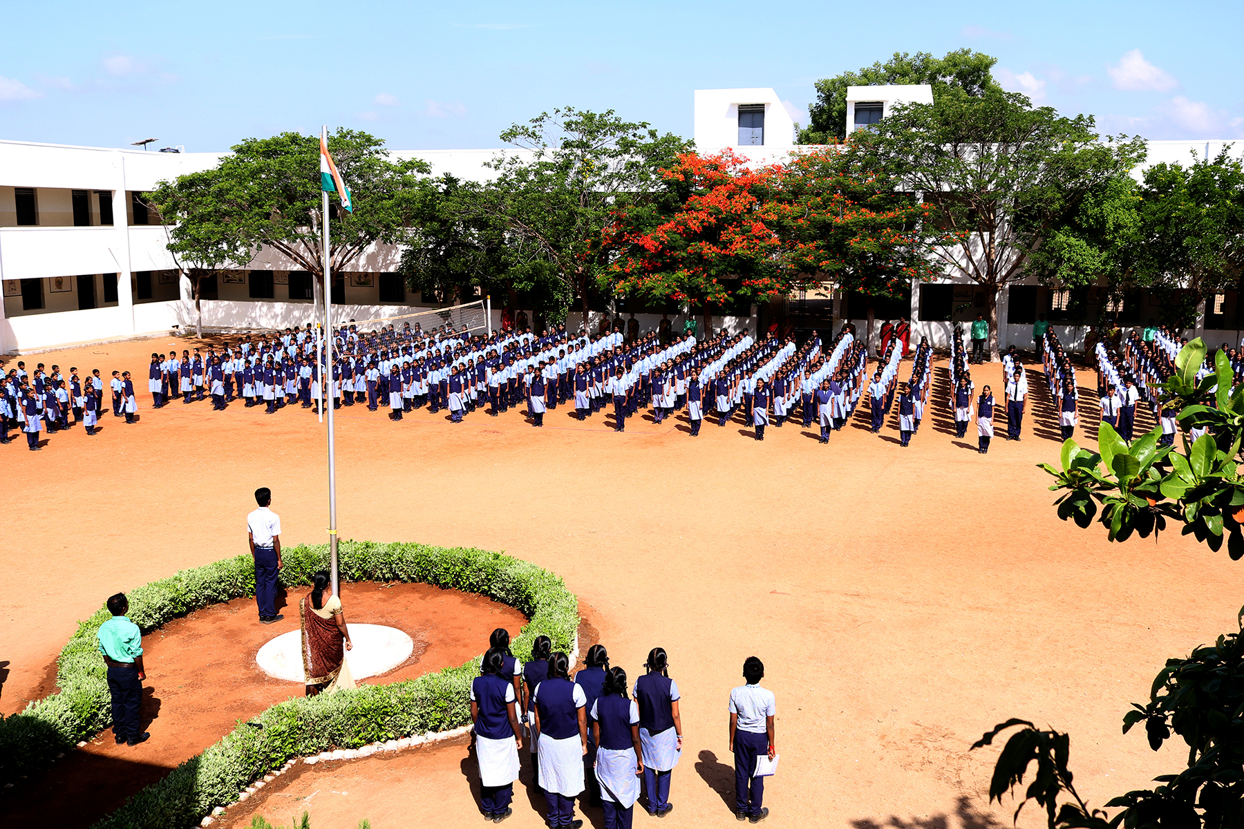 Die Schüler*innen stehen in geordneten Reihen im Schulhof und nehmen an der täglichen Morgenversammlung teil.
