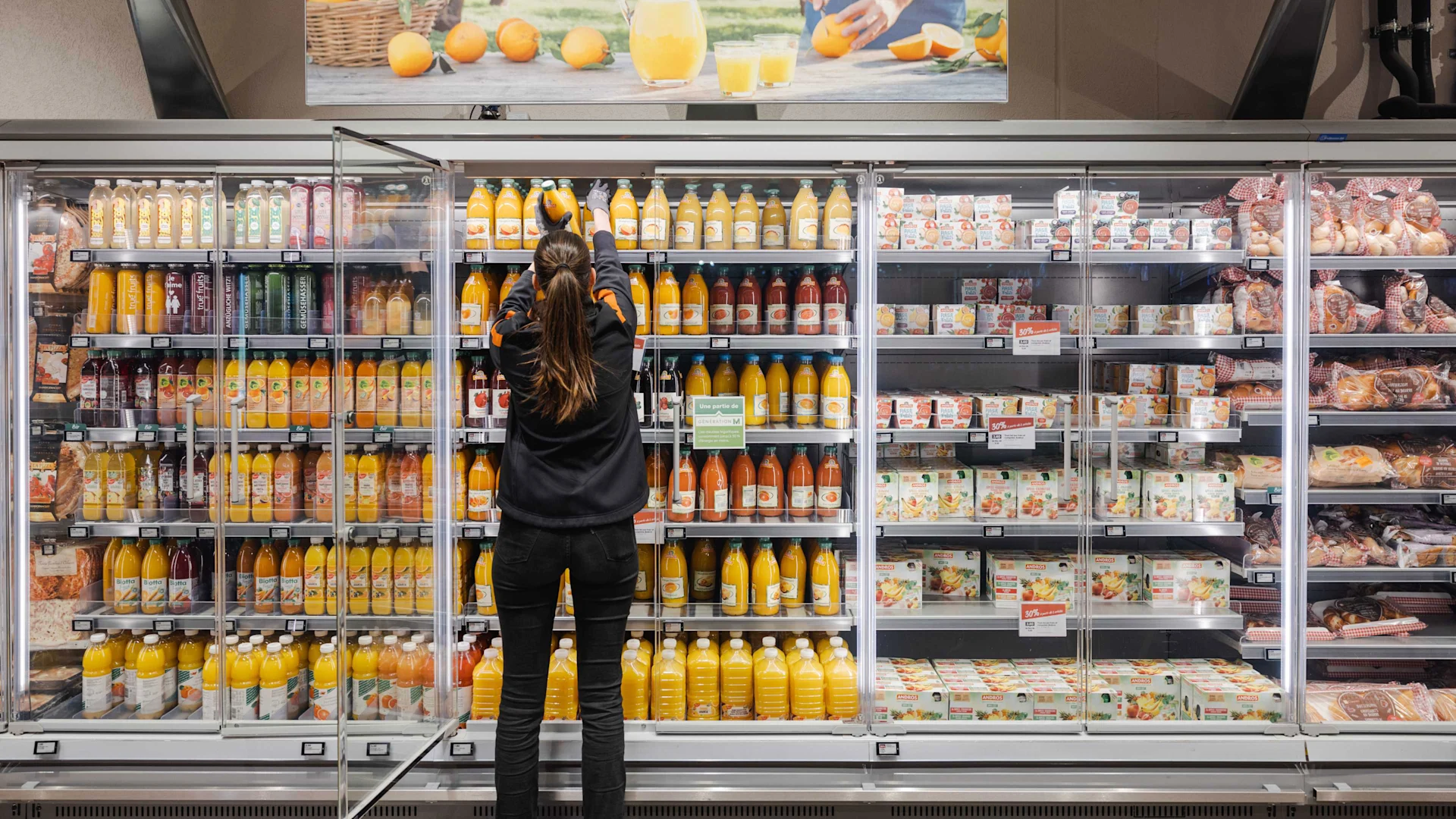 An employee fills a chiller cabinet with fruit juices
