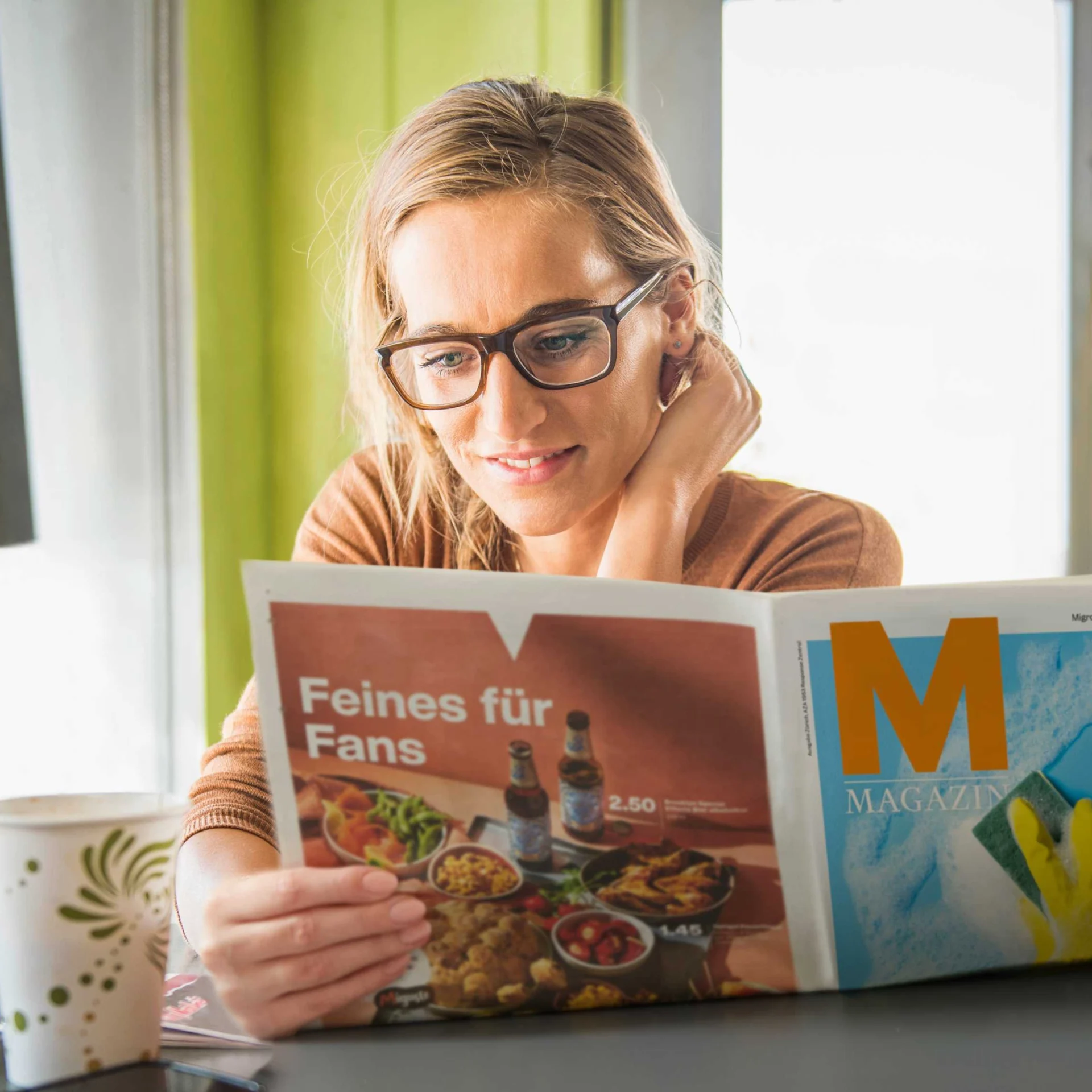 Eine Frau liest im Migros Magazin