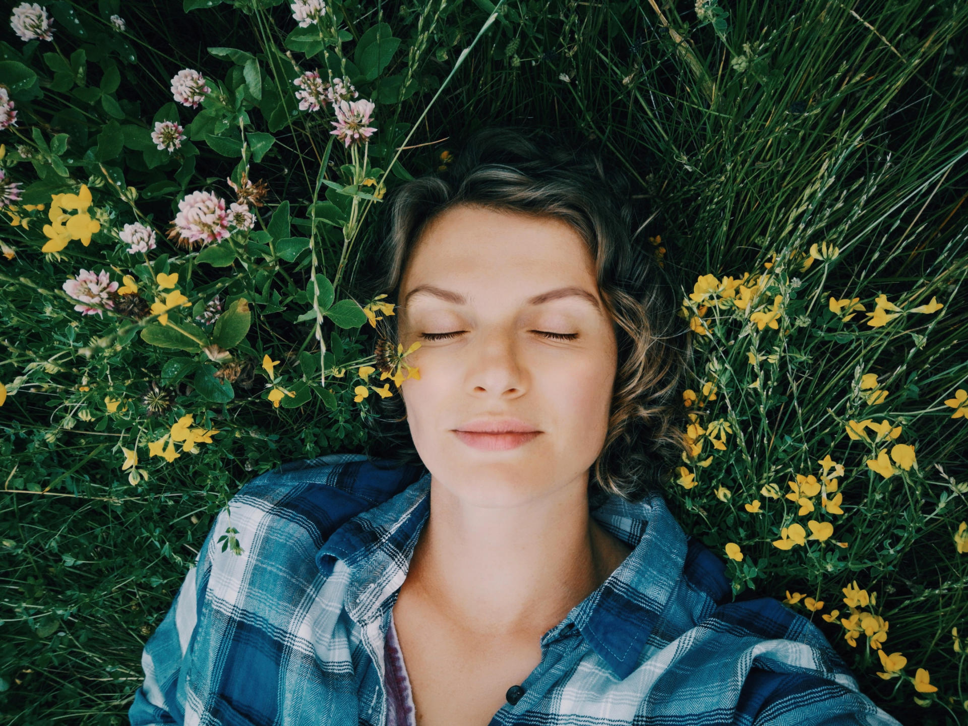 Eine Frau liegt mit geschlossenen Augen in einem Blumenfeld