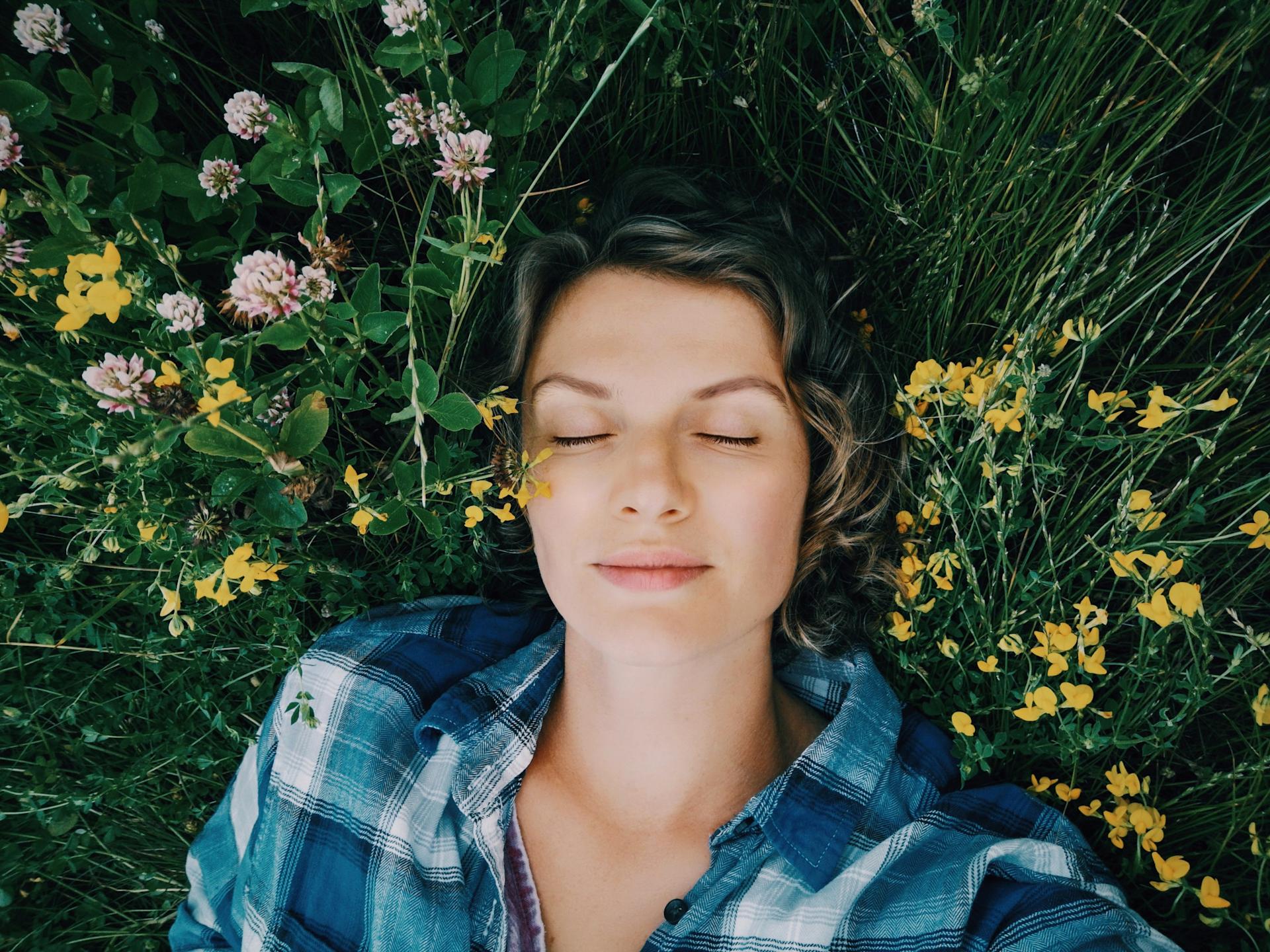 Une femme est couchée les yeux fermés dans un champ de fleurs