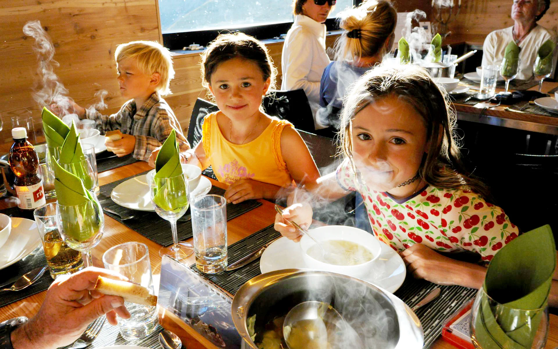 Des enfants mangent une soupe chaude dans une cabane de montagne.
