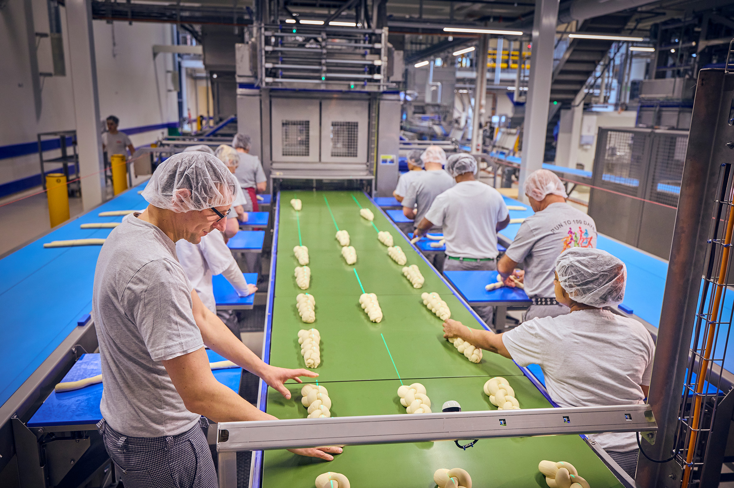 Die Zöpfe werden genau auf dem Förderband platziert.