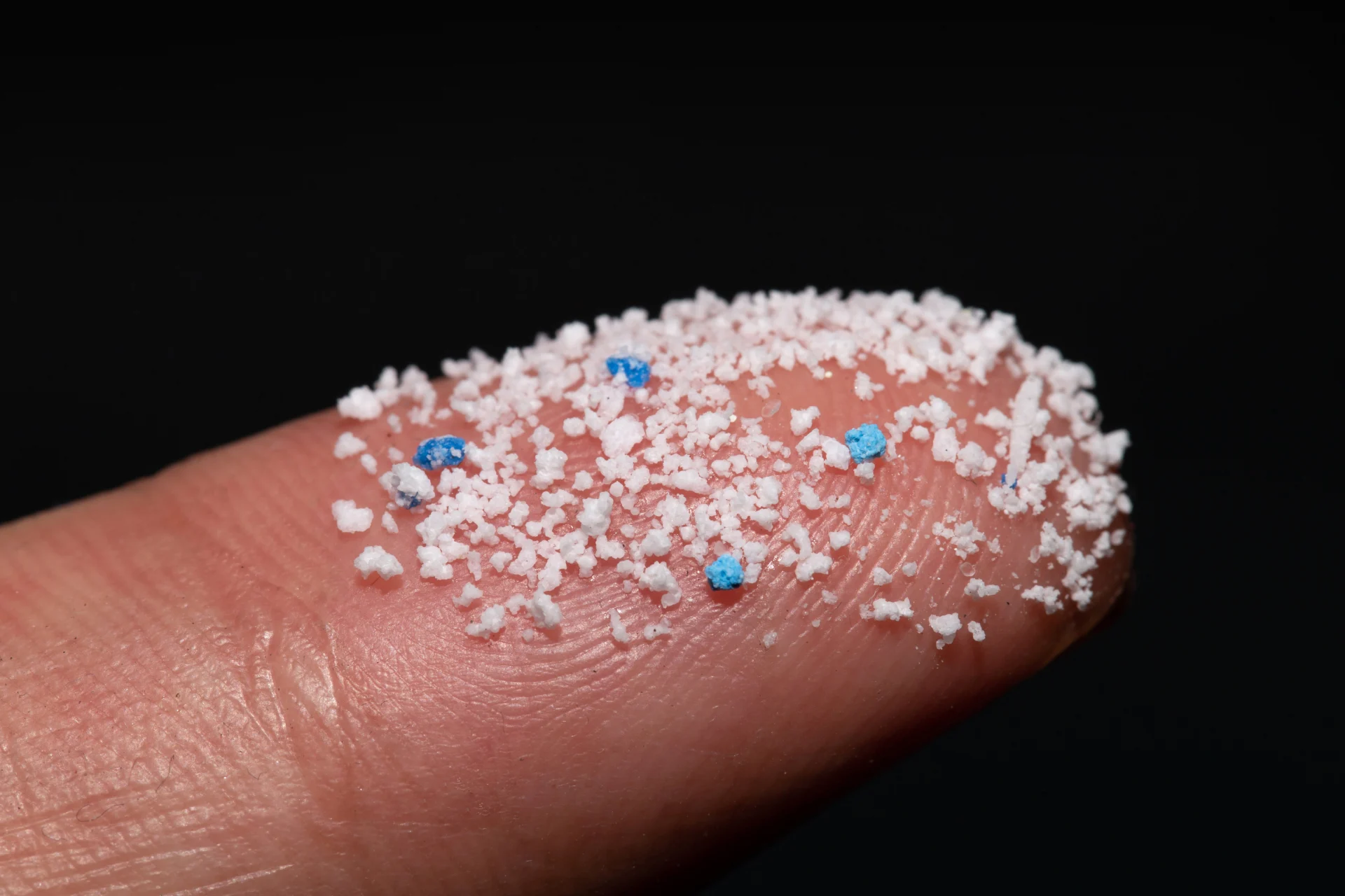 Microplastic in different colours on a fingertip
