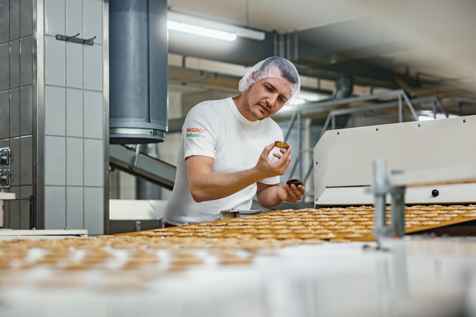 Un opérateur de Delica SA contrôle un biscuit sur le tapis roulant.