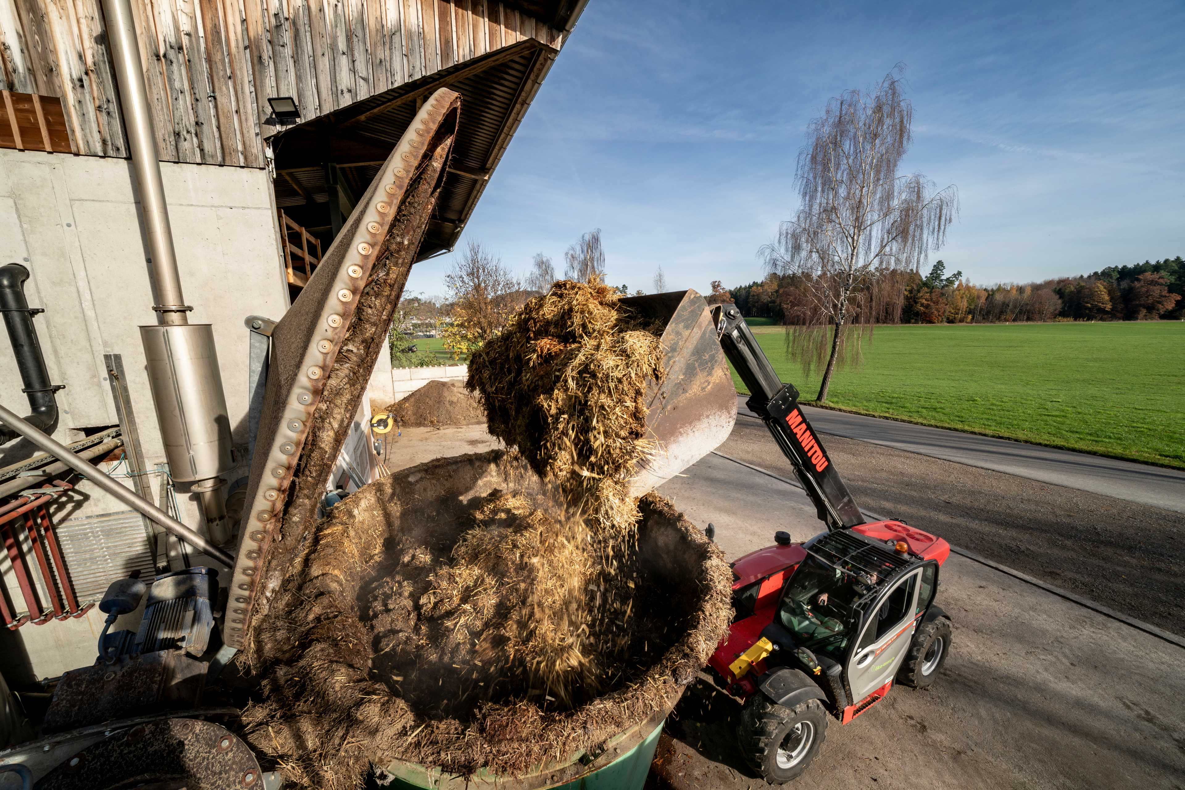L'agricoltore Michael Müller inserisce il letame nel sistema di alimentazione dei materiali solidi con il sollevatore telescopico.