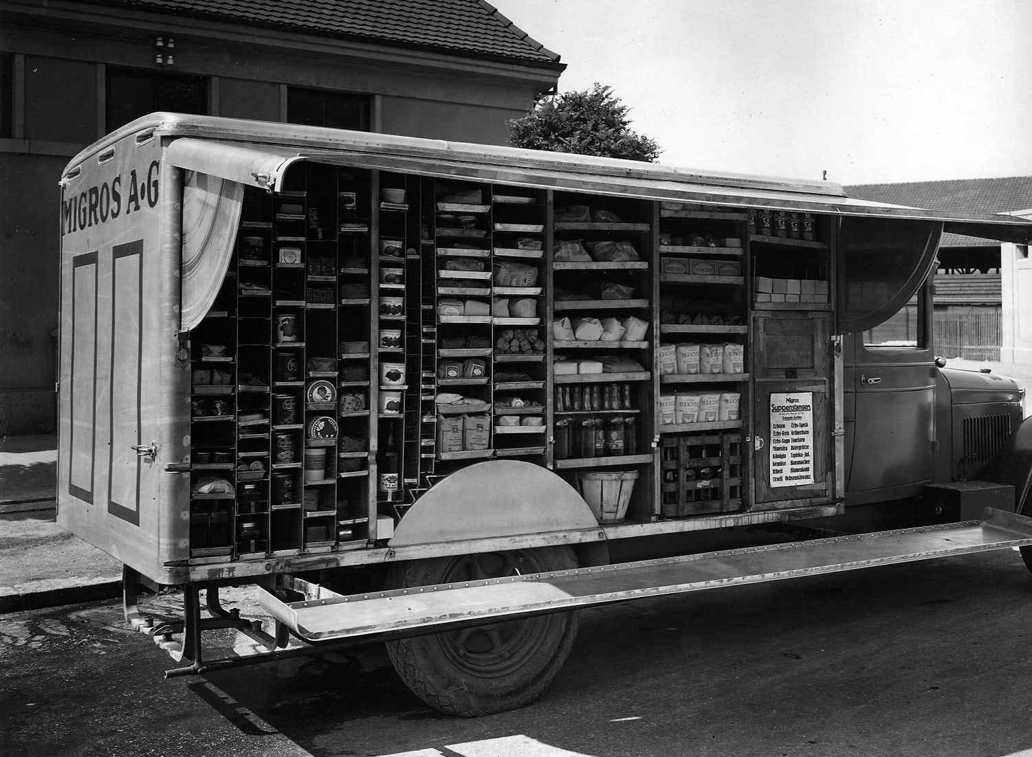 Sales trolley open at the side and filled with Migros products (1932).