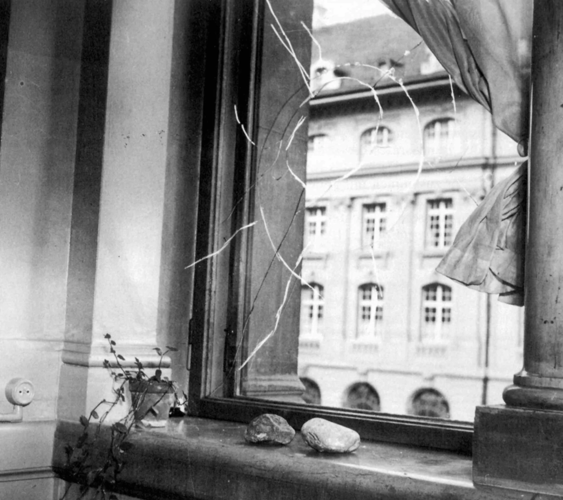 A broken window with a stone on the windowsill.