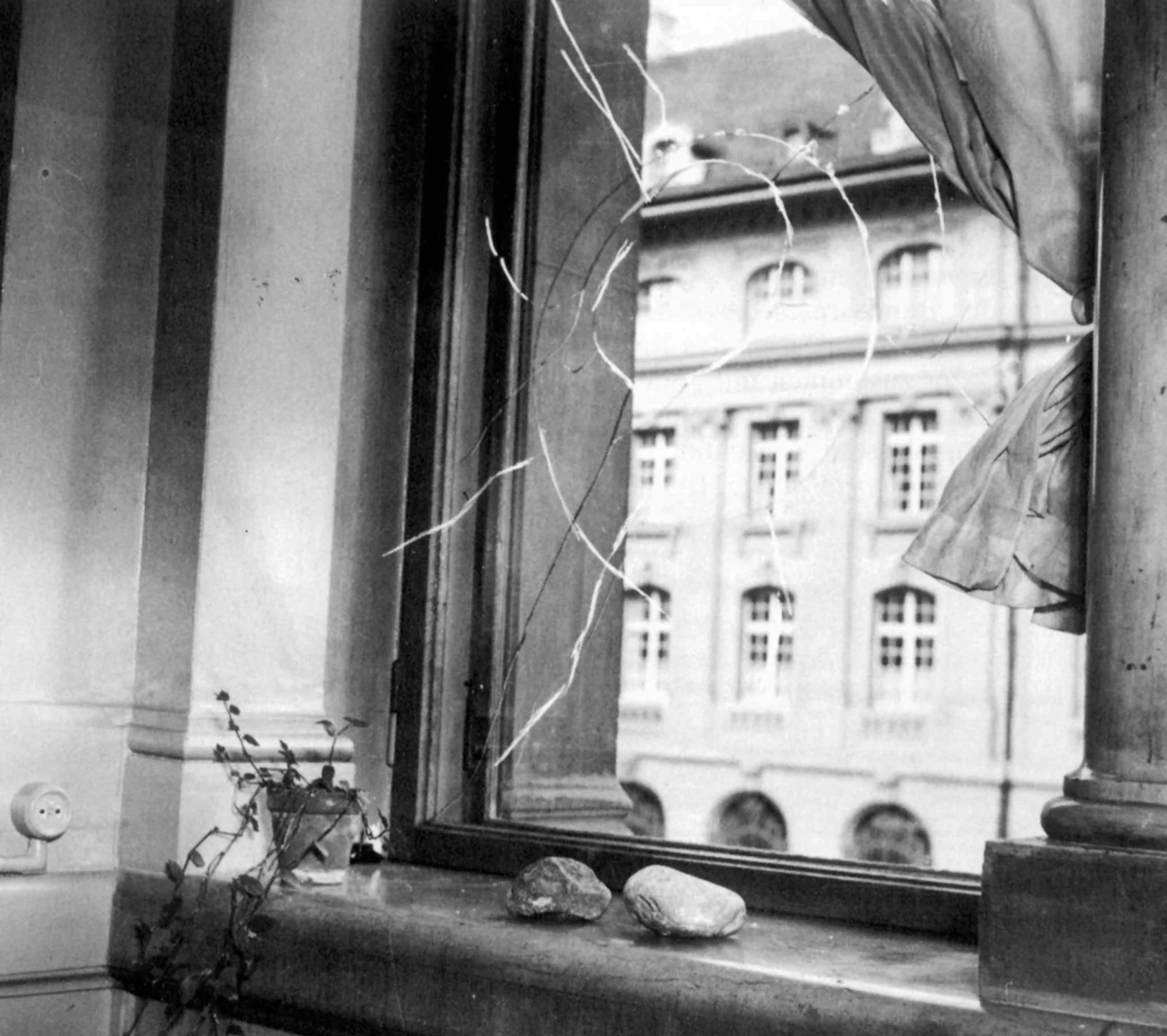 A broken window with a stone on the windowsill.