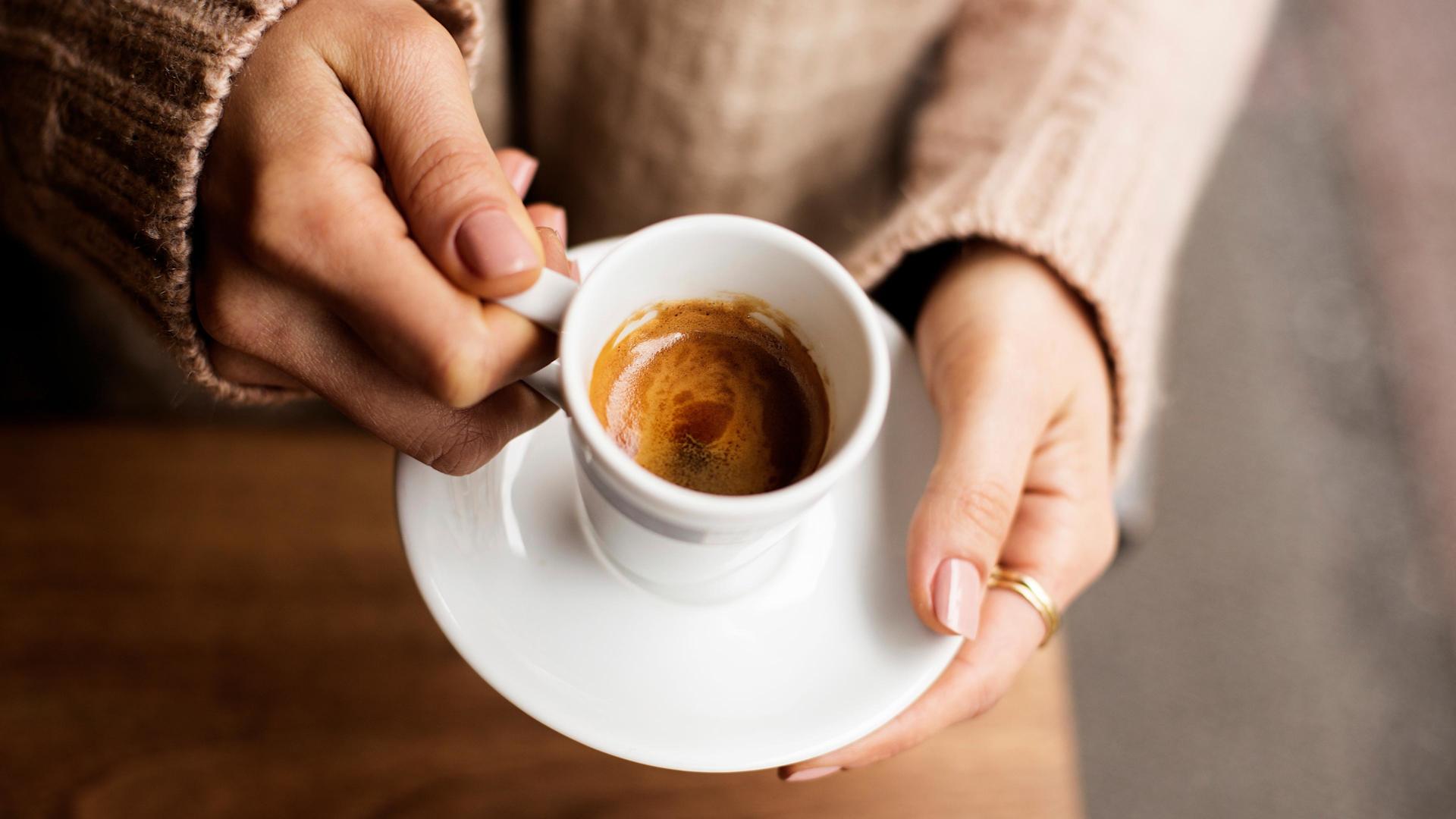 Mani di donna che tengono una tazza di espresso