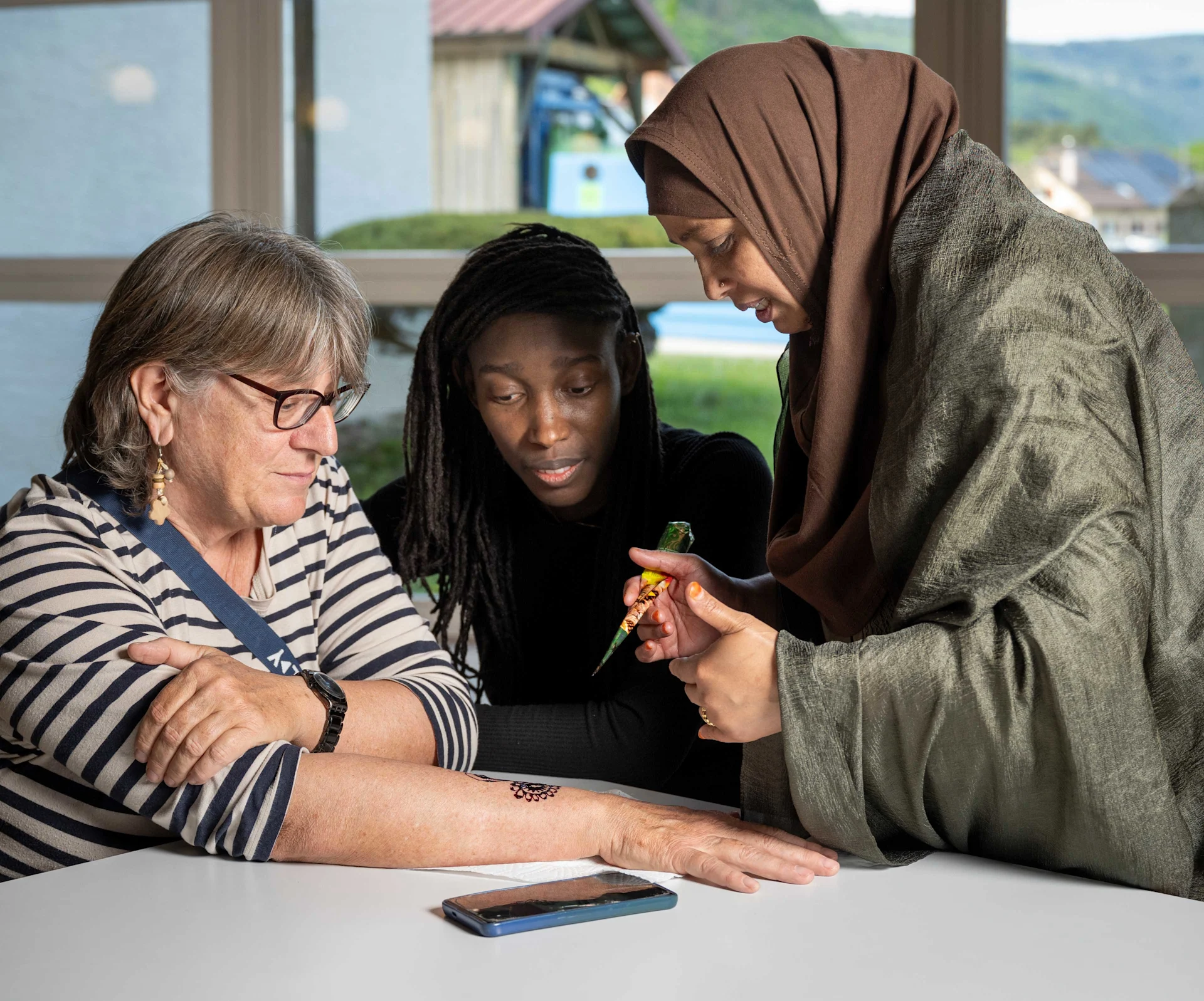 Mireille Keita-Gilgien assiste à la création d'un tatouage au henné