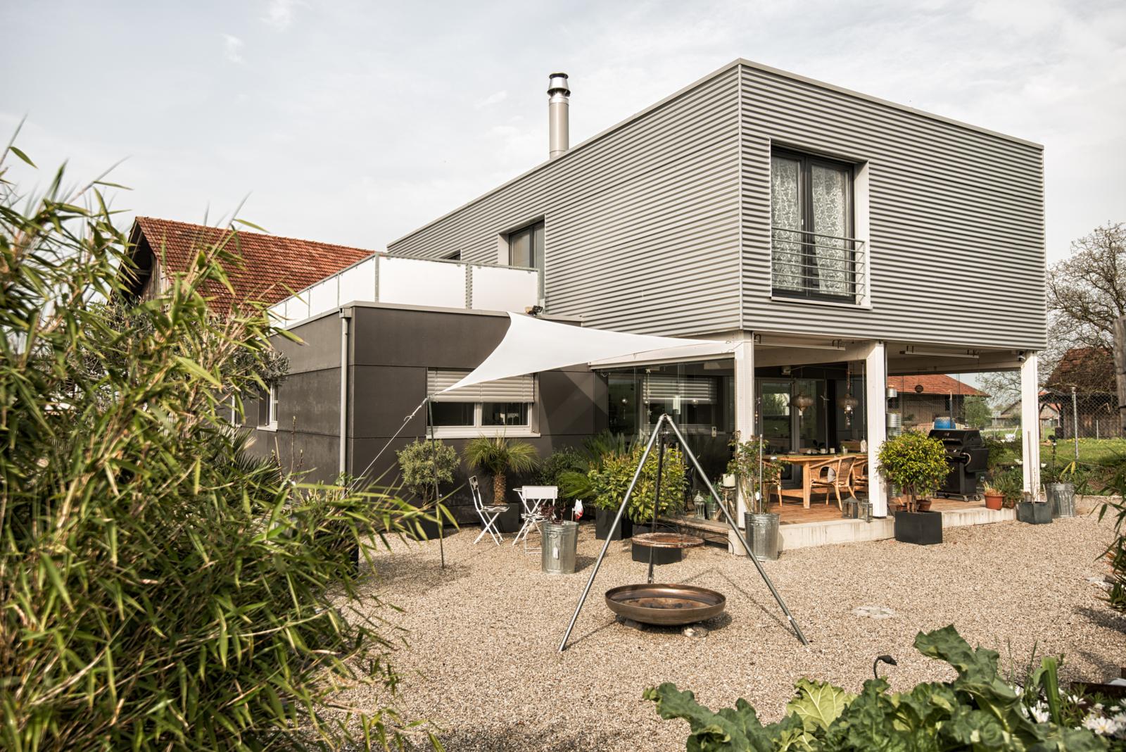 A modern detached house with terrace, various plants for greenery and a barbecue.