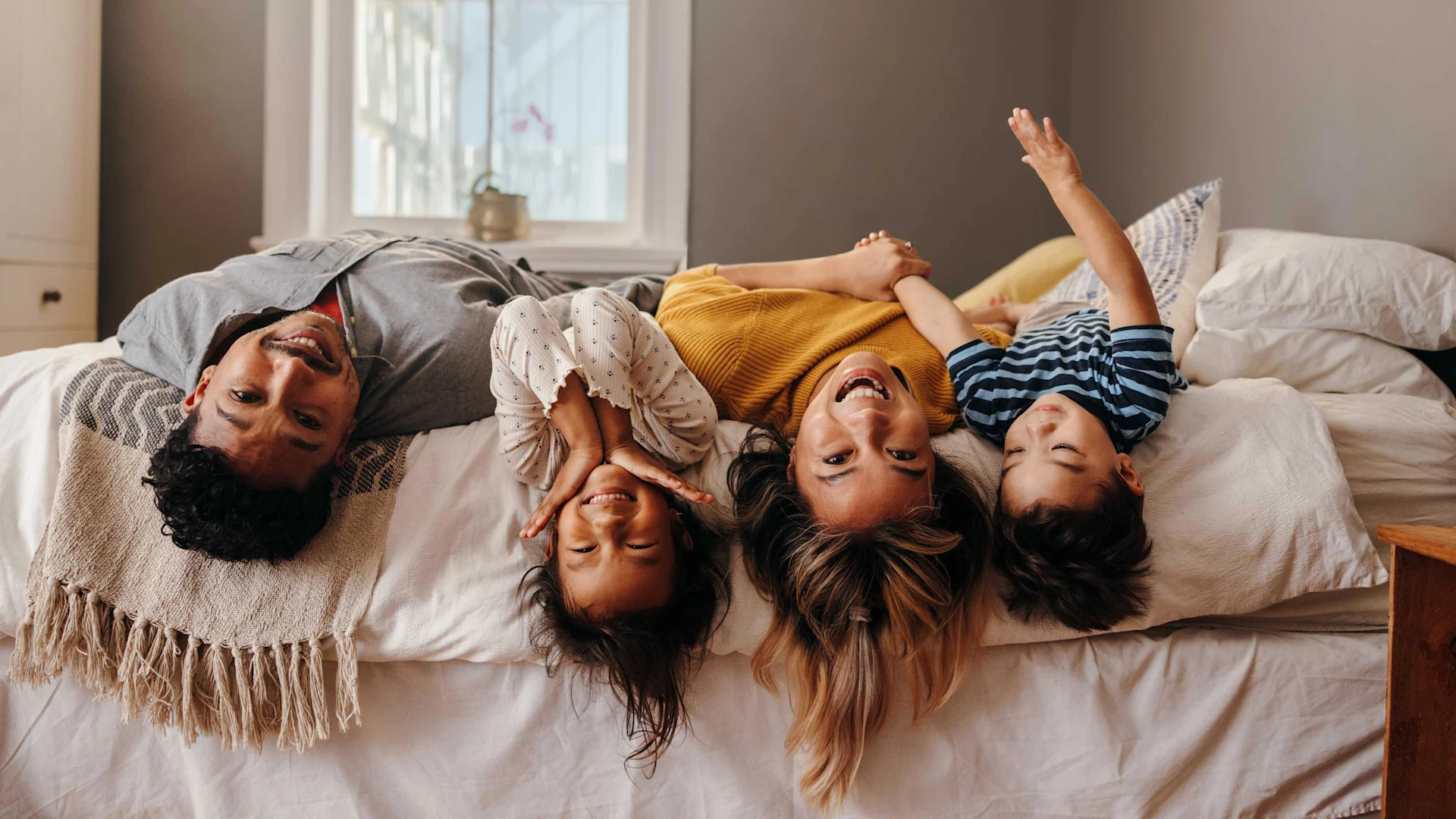 Una famiglia con due bambini si sdraia su un letto e ride