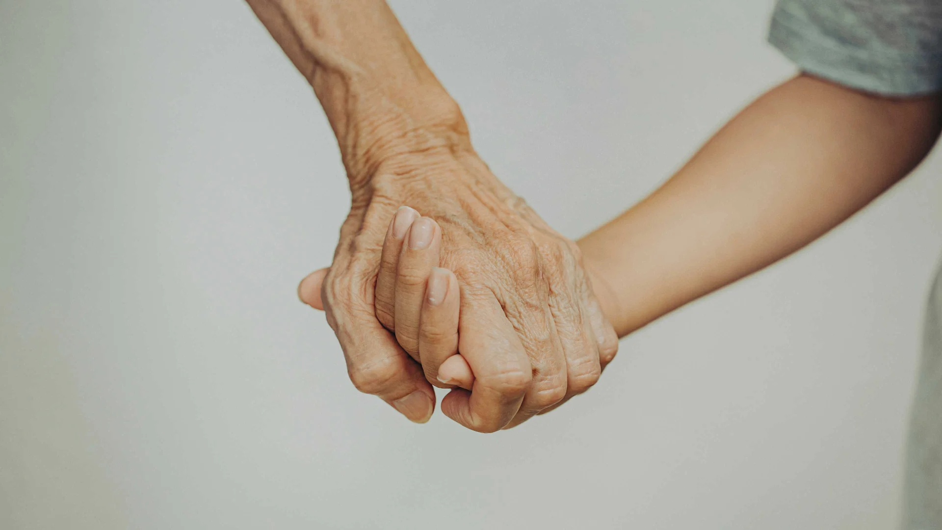 Holding hands of a child and an elderly person.