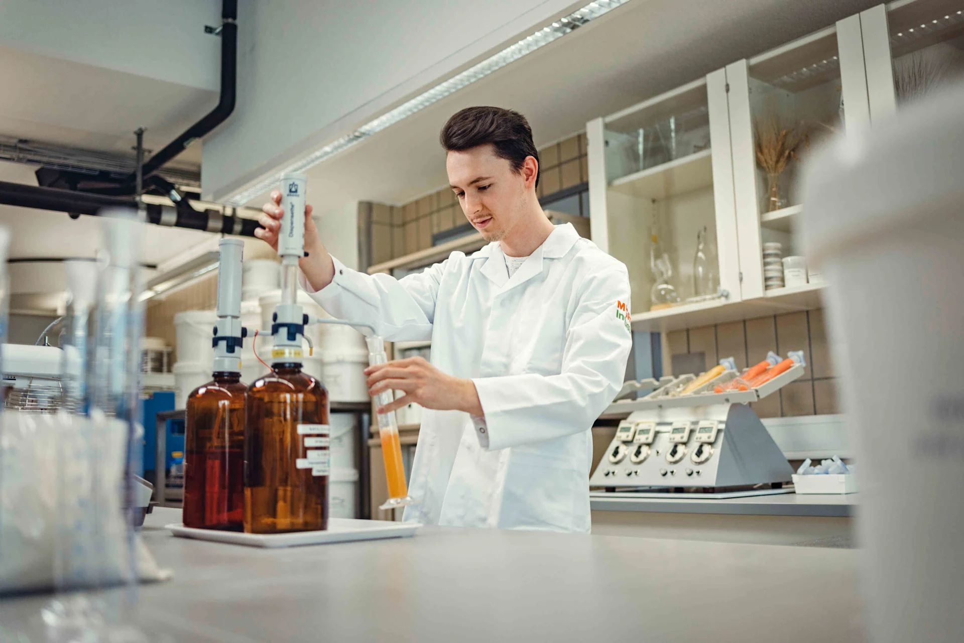 Laboratory employee transfers liquid from one container to another.