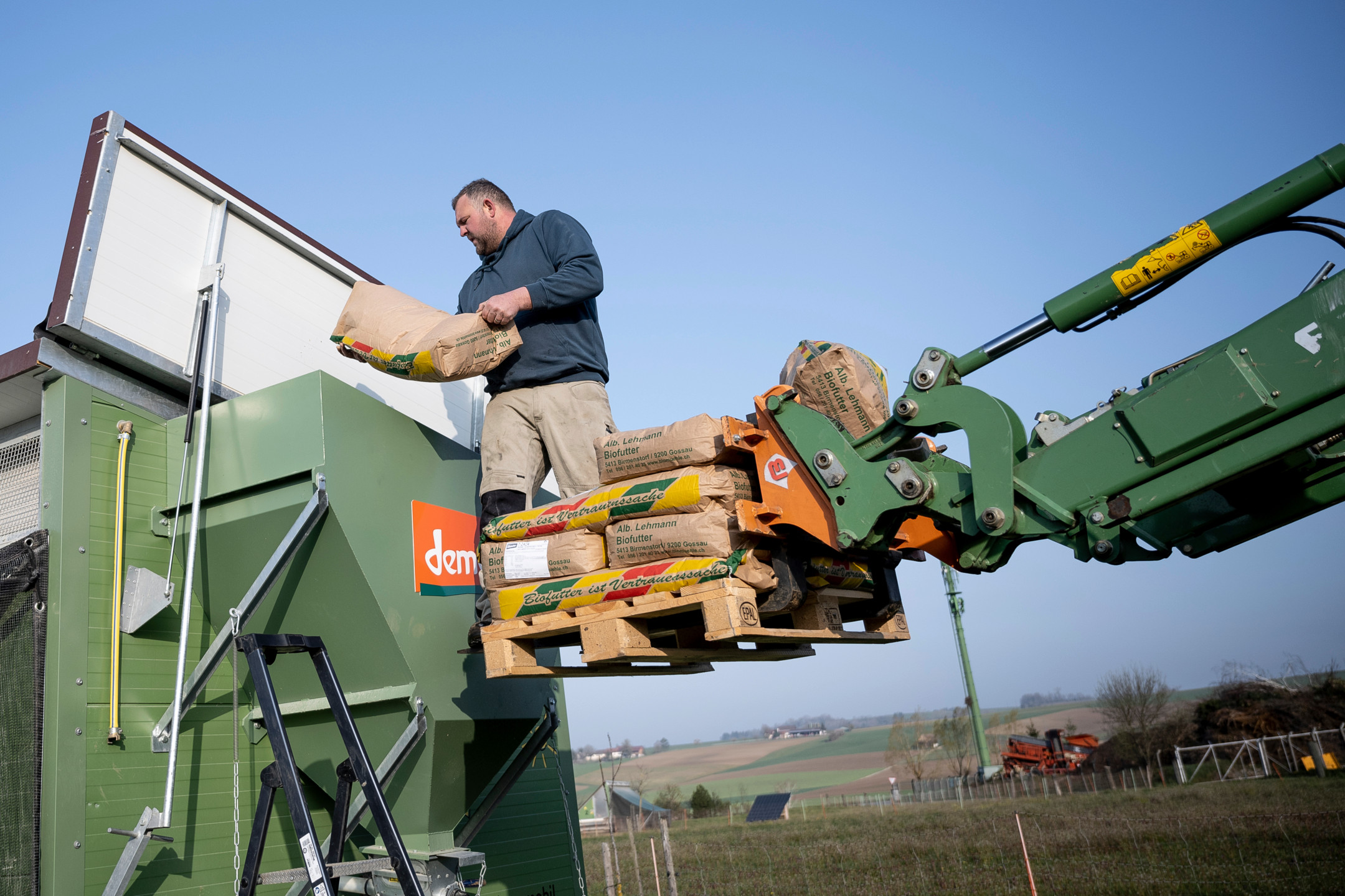 Farmer Anno Lutke Schipholt empties bags into a hopper from the forklift attachment of a tractor