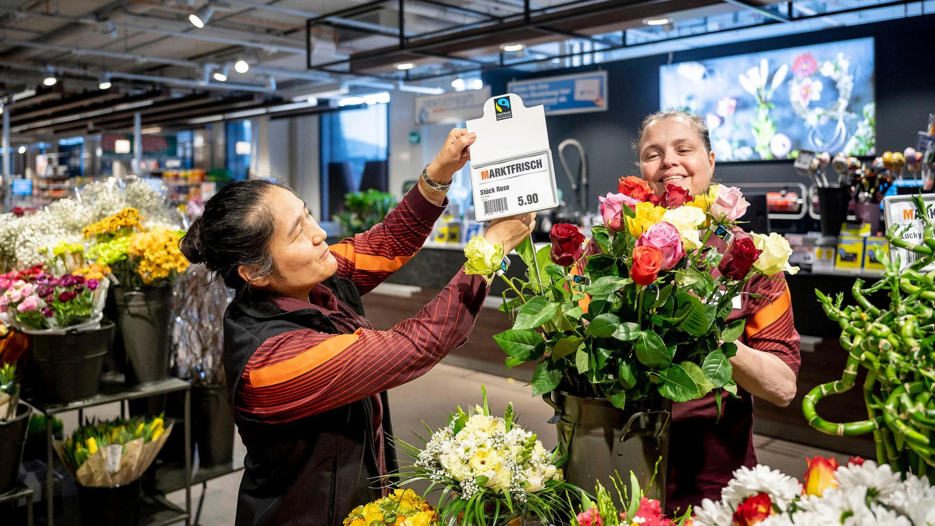Zwei Mitarbeiterinnen der Migros der Blumenabteilung binden zusammen einen Blumenstrauss.