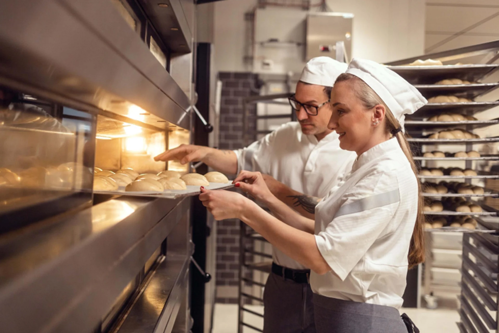 Due dipendenti di una panetteria mettono il pane in forno