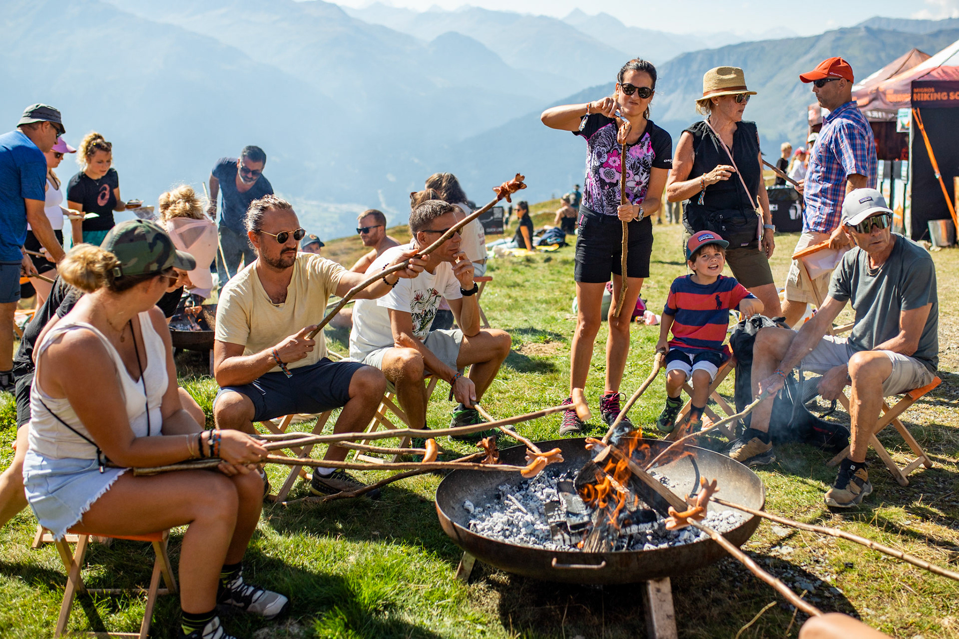Jeunes et moins jeunes sont assis autour d’un brasero et font des grillades avec des bâtons.