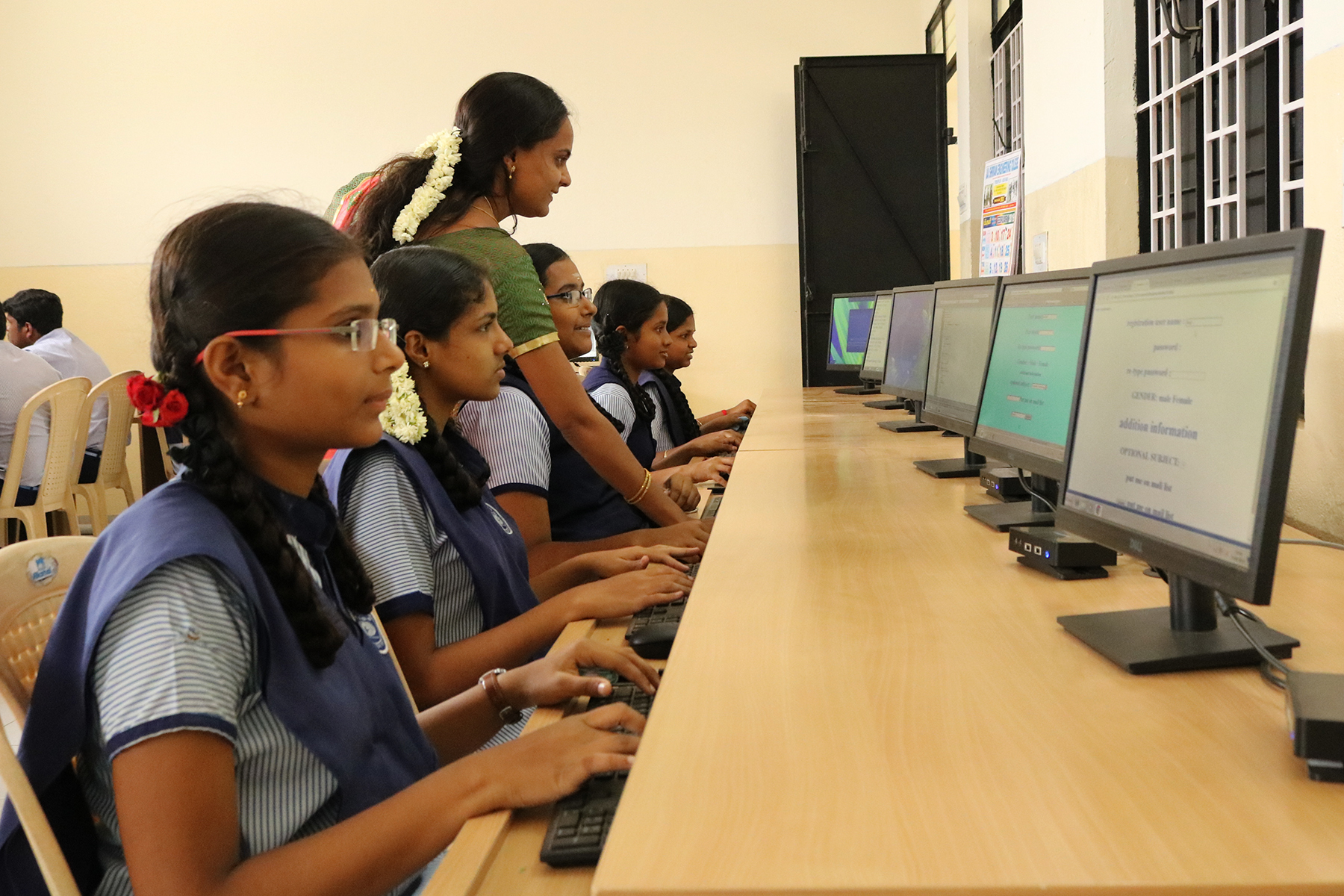 Mehrere Schülerinnen sitzen an einem langen Tisch und arbeiten am Computer.