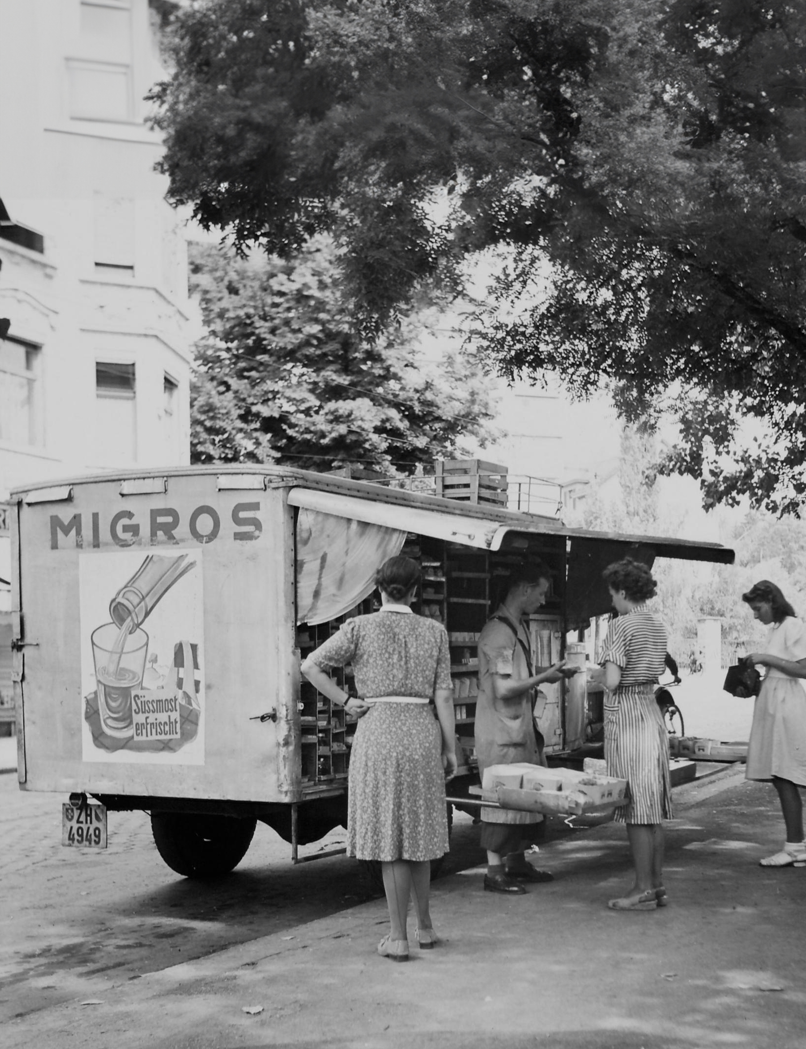 A black-and-white photograph of a moving sales vehicle.