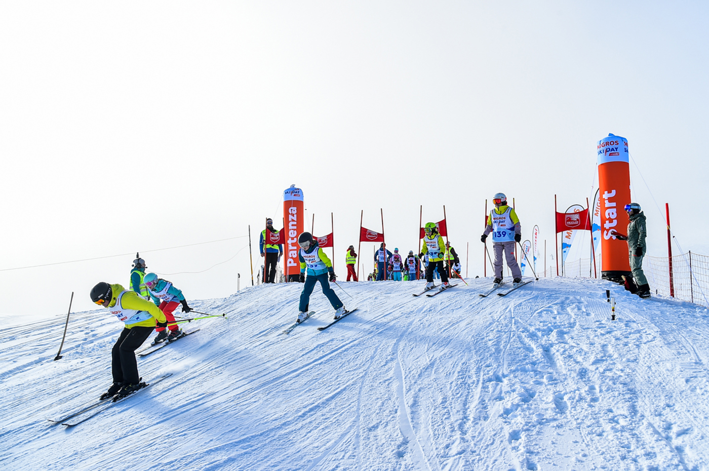 Persone che si posizionano con gli sci all'inizio di una pista di slalom e scendono lungo la pista.