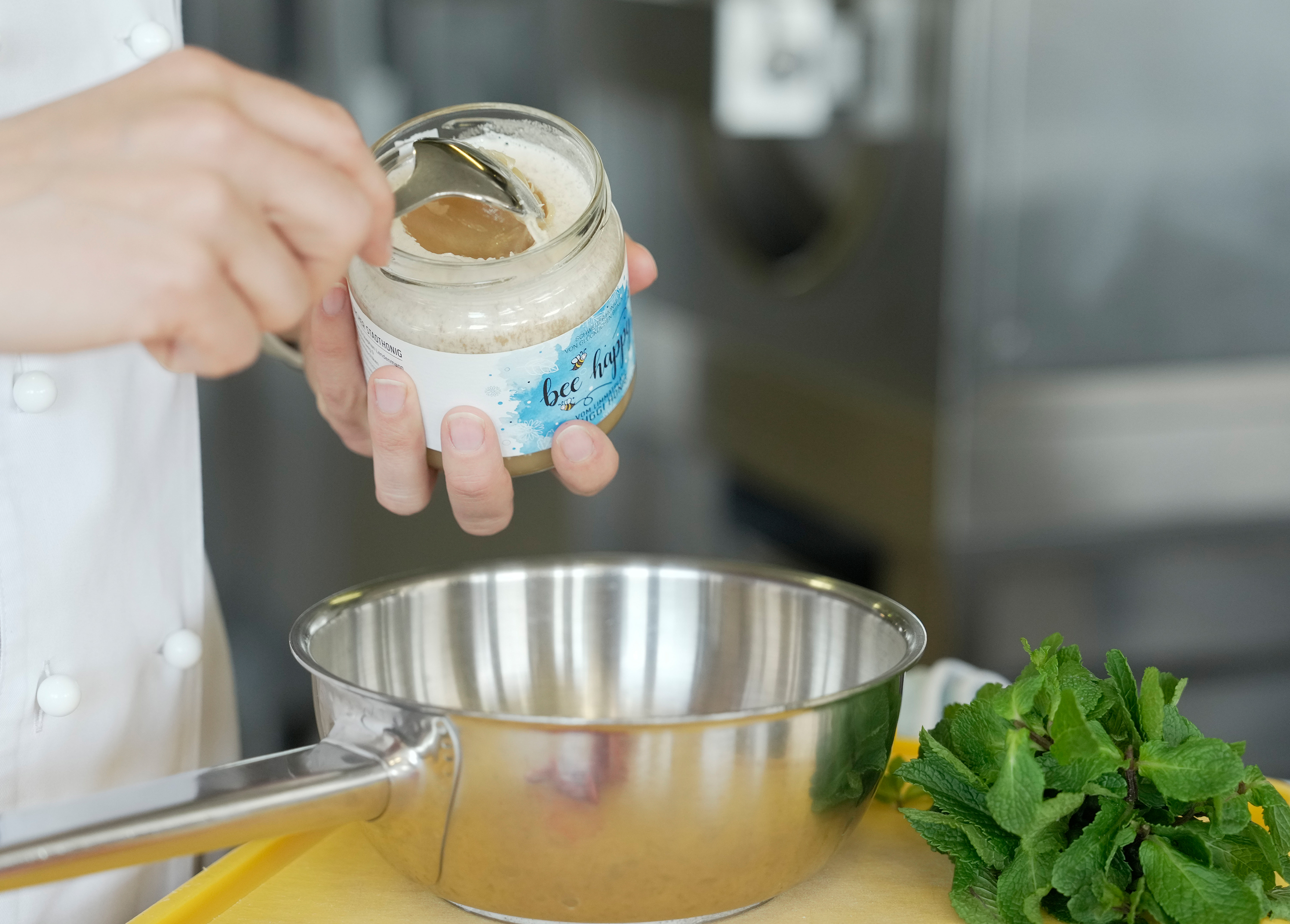 Mirjam Lendenmann nimmt mit einem Löffel Honig aus einem Honigglas.