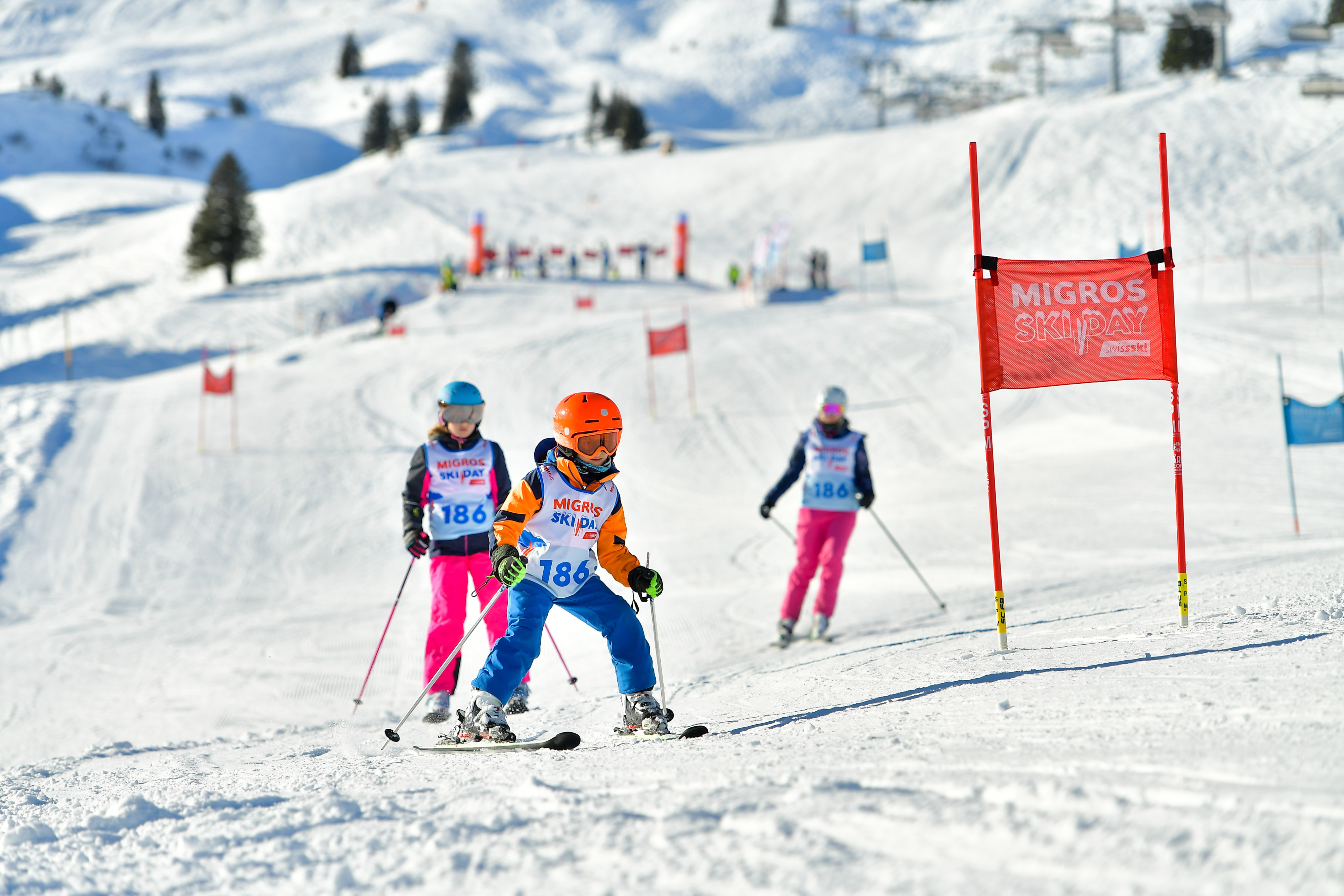 Bambini che sciano passando accanto alle bandiere dello slalom.