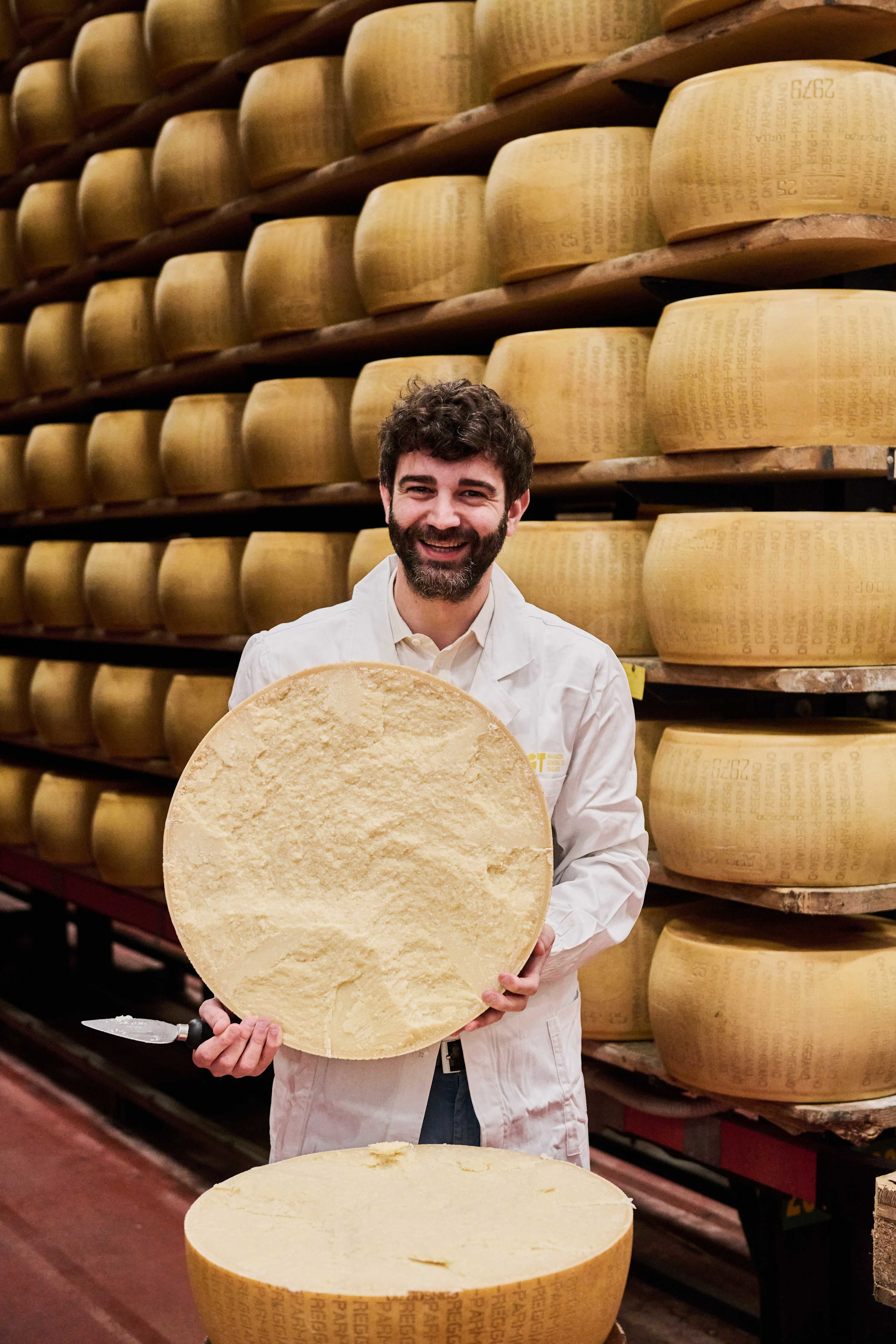 Fabrizio Zampinetti holds a halved Parmesan wheel in his hands.