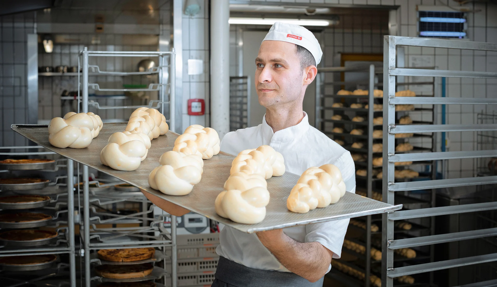 Fuad holds a tray of braided bread dough