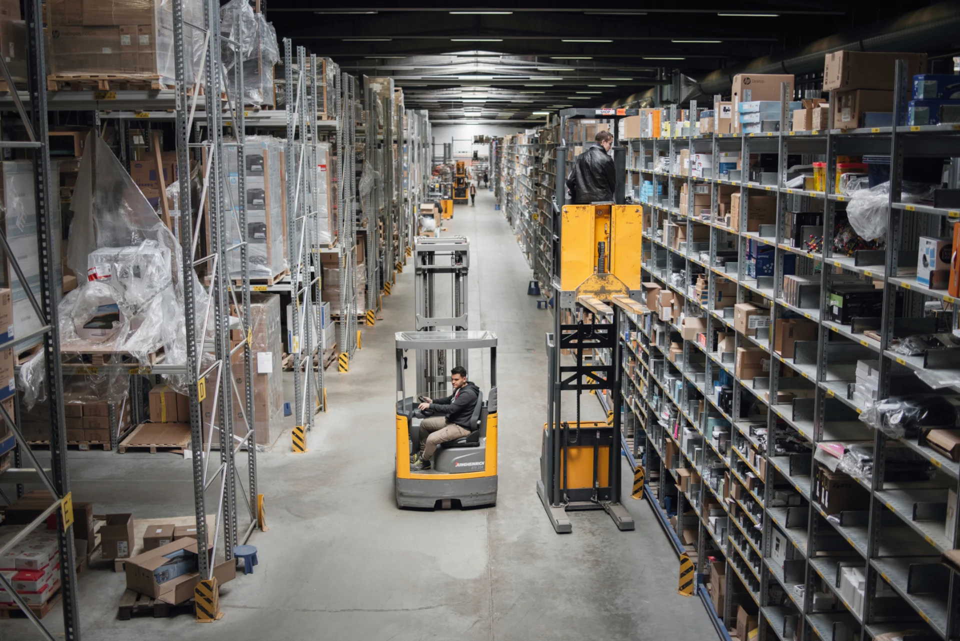 A large warehouse with storage racks up to the ceiling; in the middle, a forklift