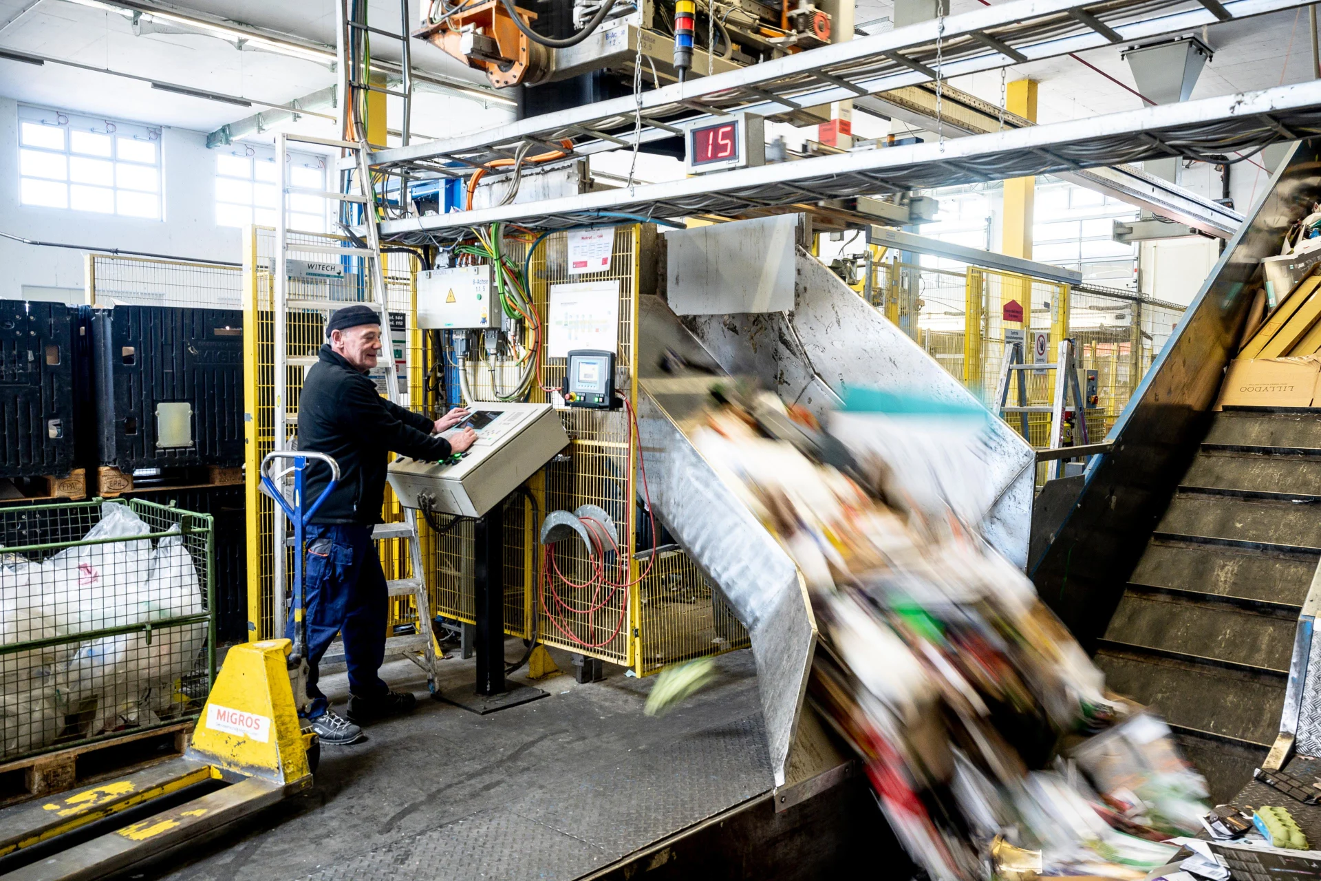 Ein Mann steht an einer Schaltzentrale in einem Recycling-Center