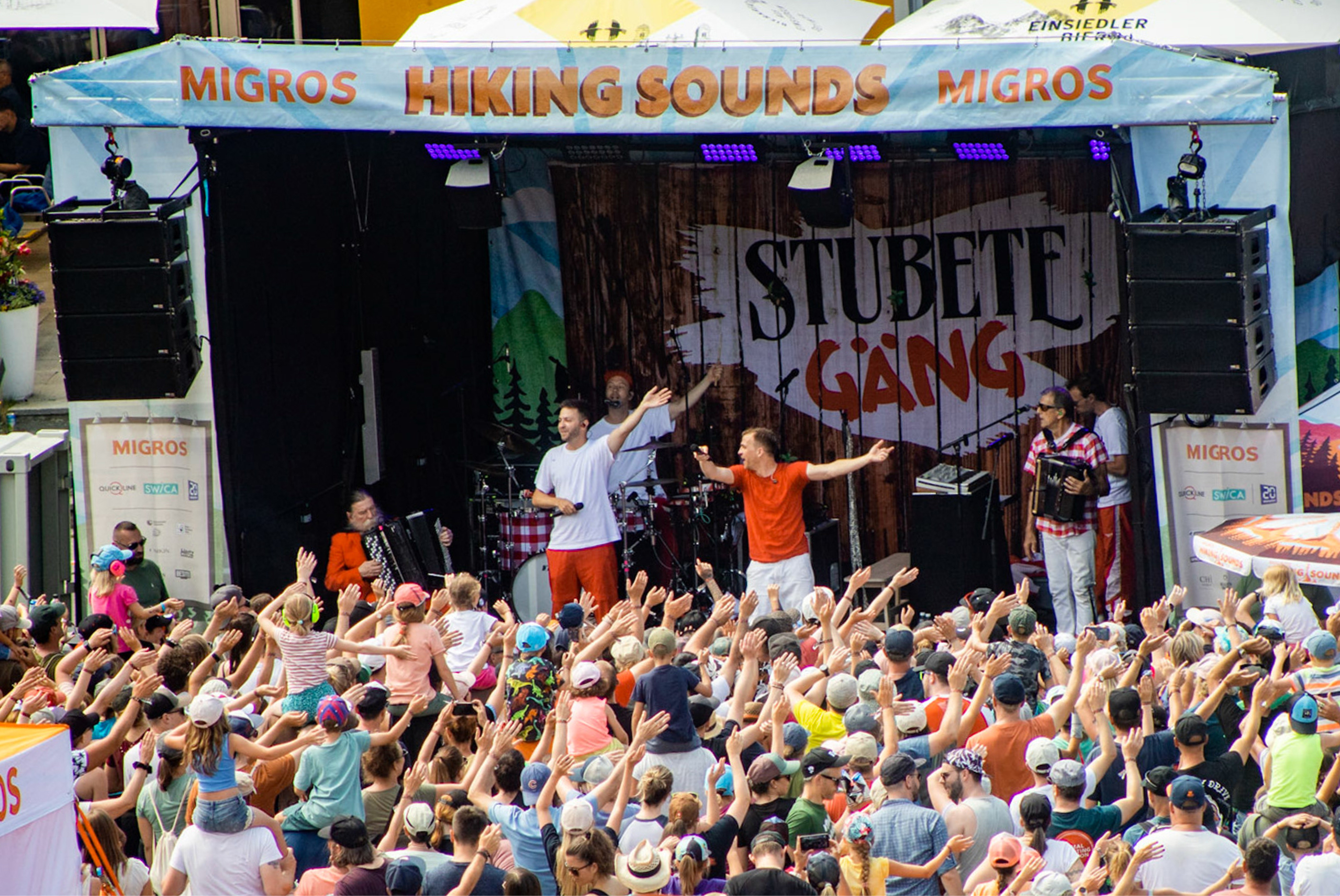 Un groupe de musique fait la fête sur une scène devant un public nombreux.