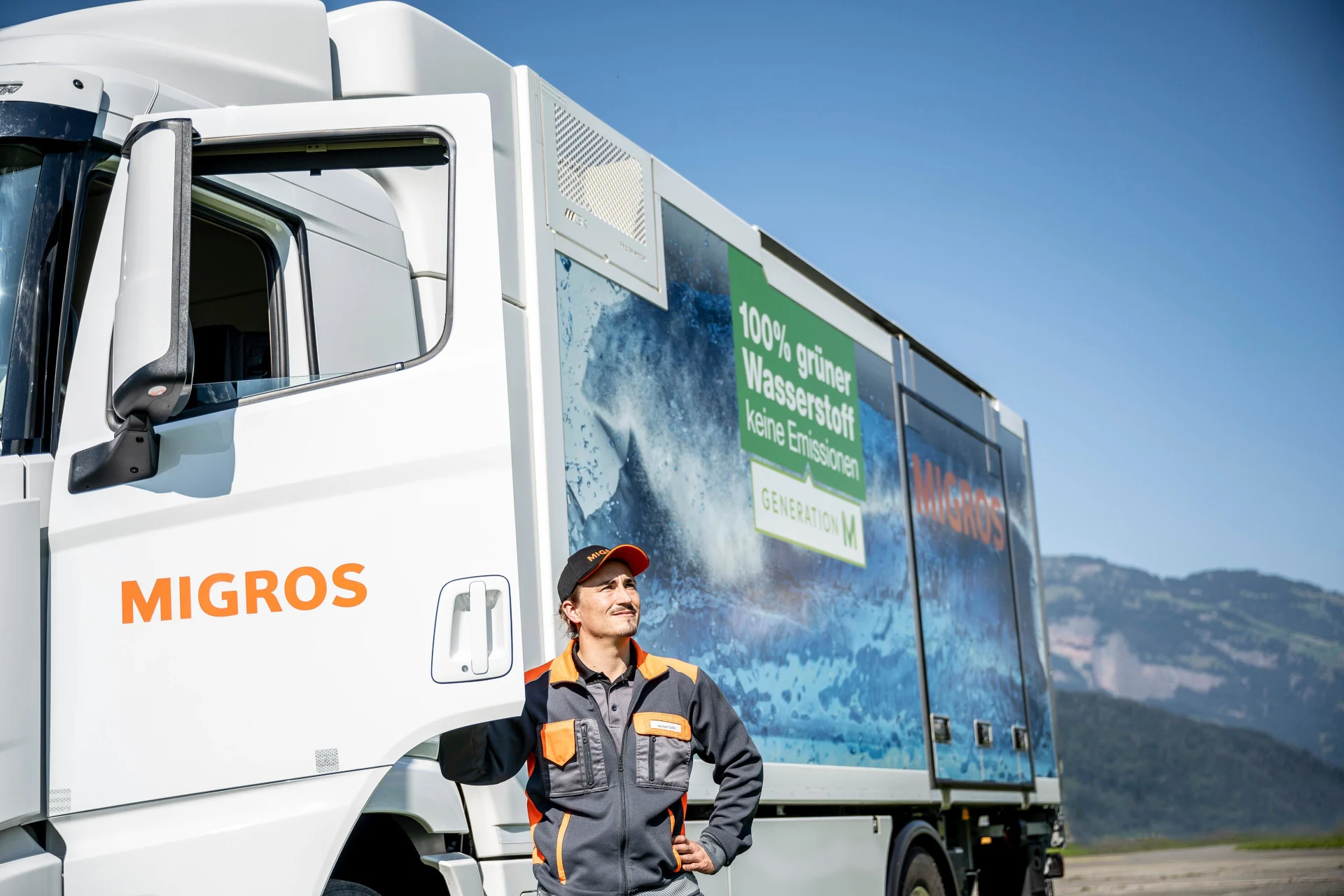 A Migros truck driver stands in front of a hydrogen truck