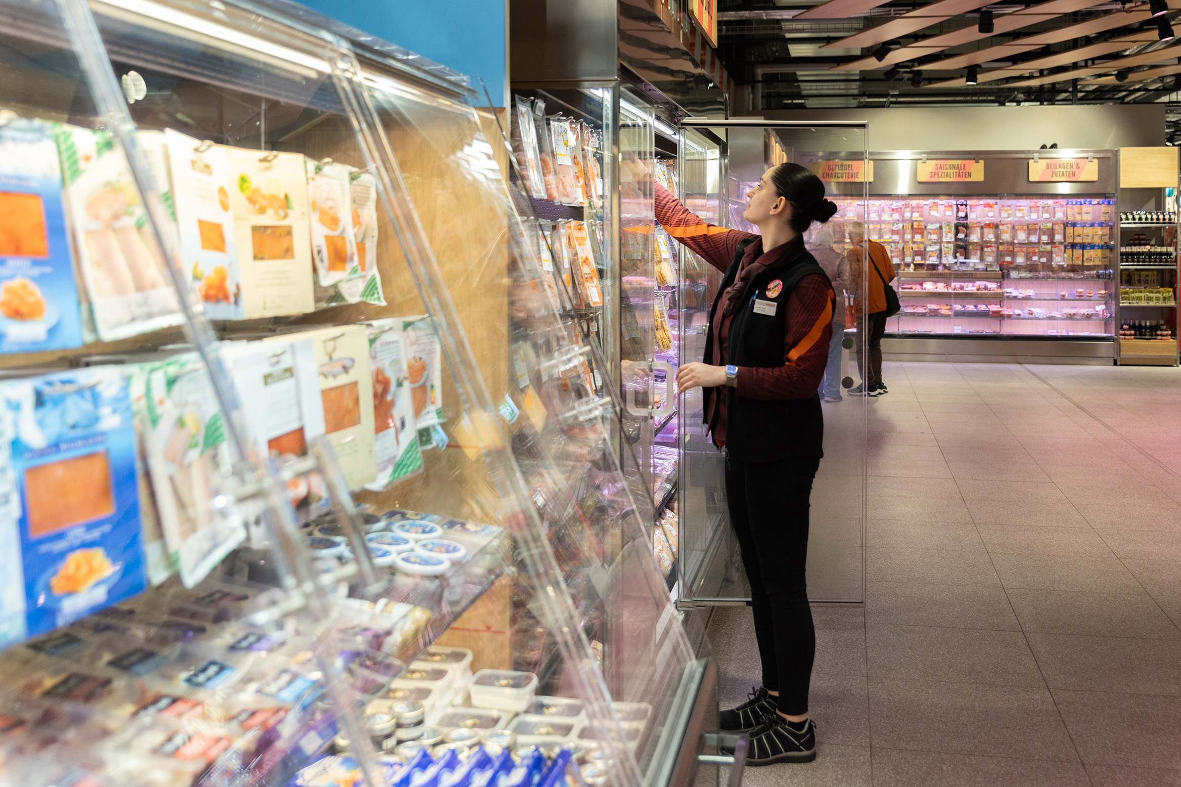 Mitarbeiterin am Kühlregal im Supermarkt