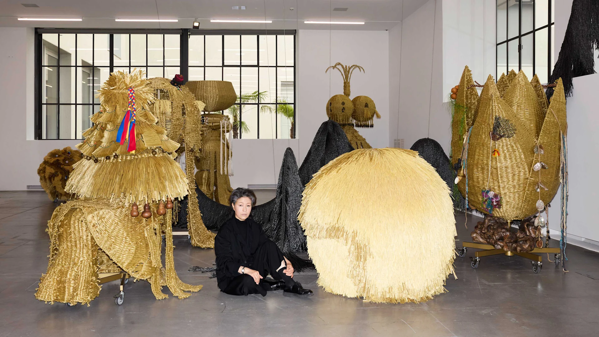 Haegue Yang sittting on the floor in front of her installations.