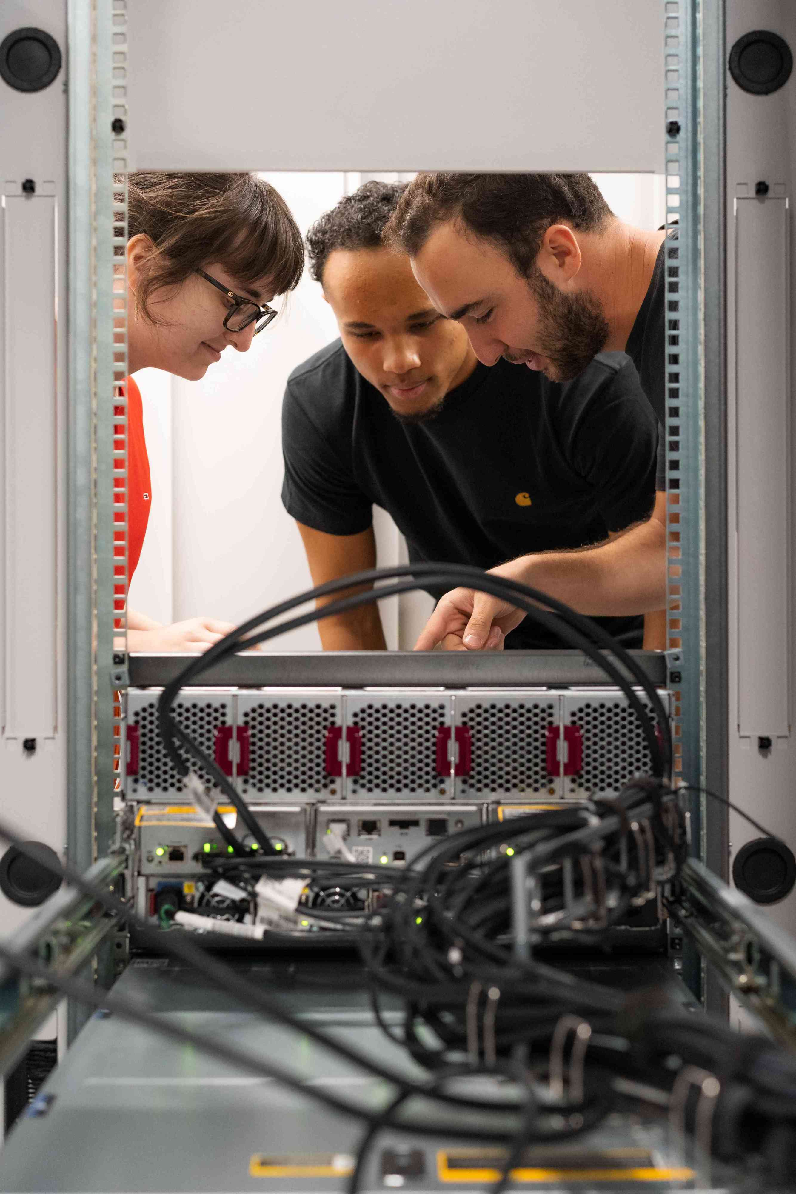 Tre apprendisti informatici si chinano su un PC aperto.