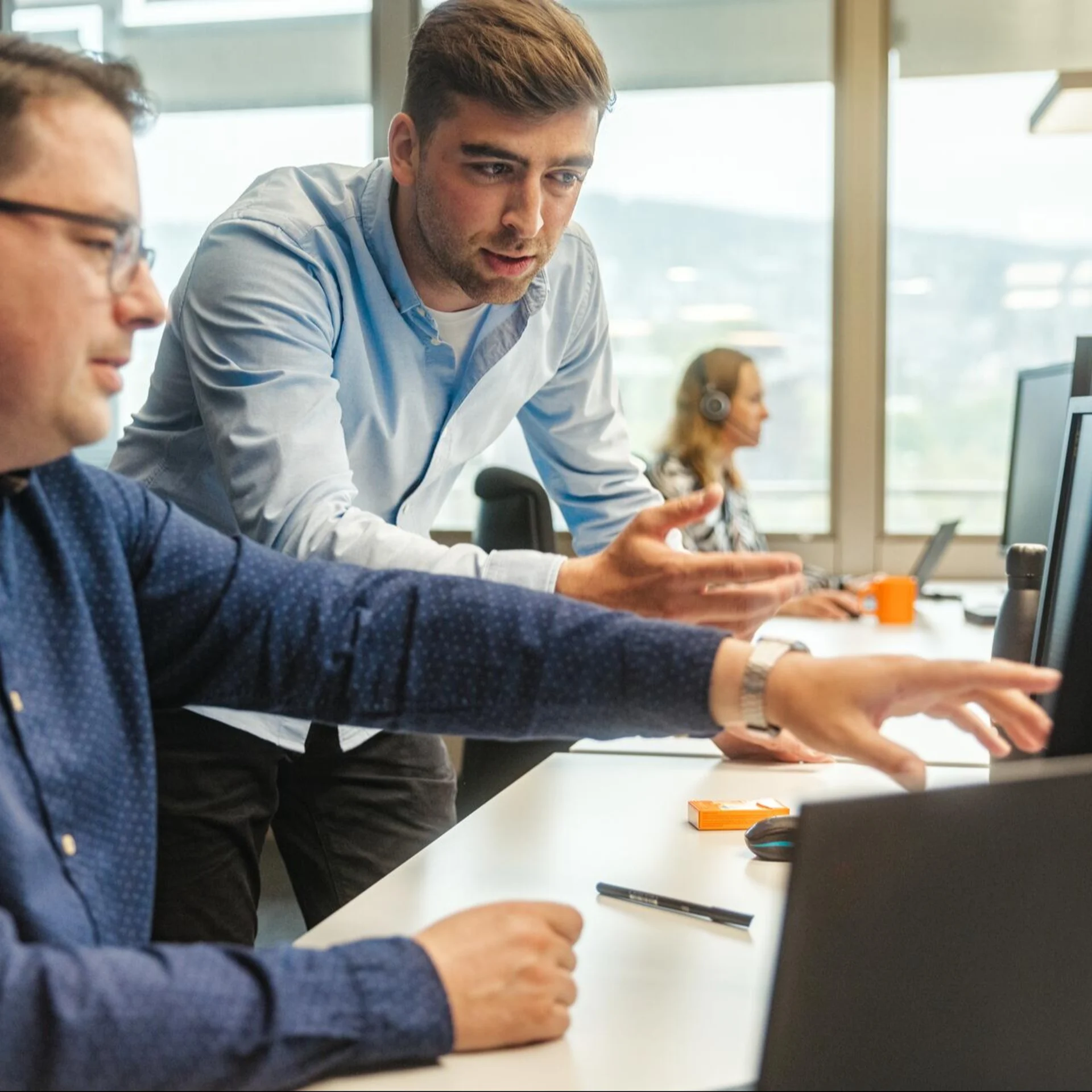 Zwei Personen am Arbeitsplatz führen eine Besprechung vor einem Bildschirm