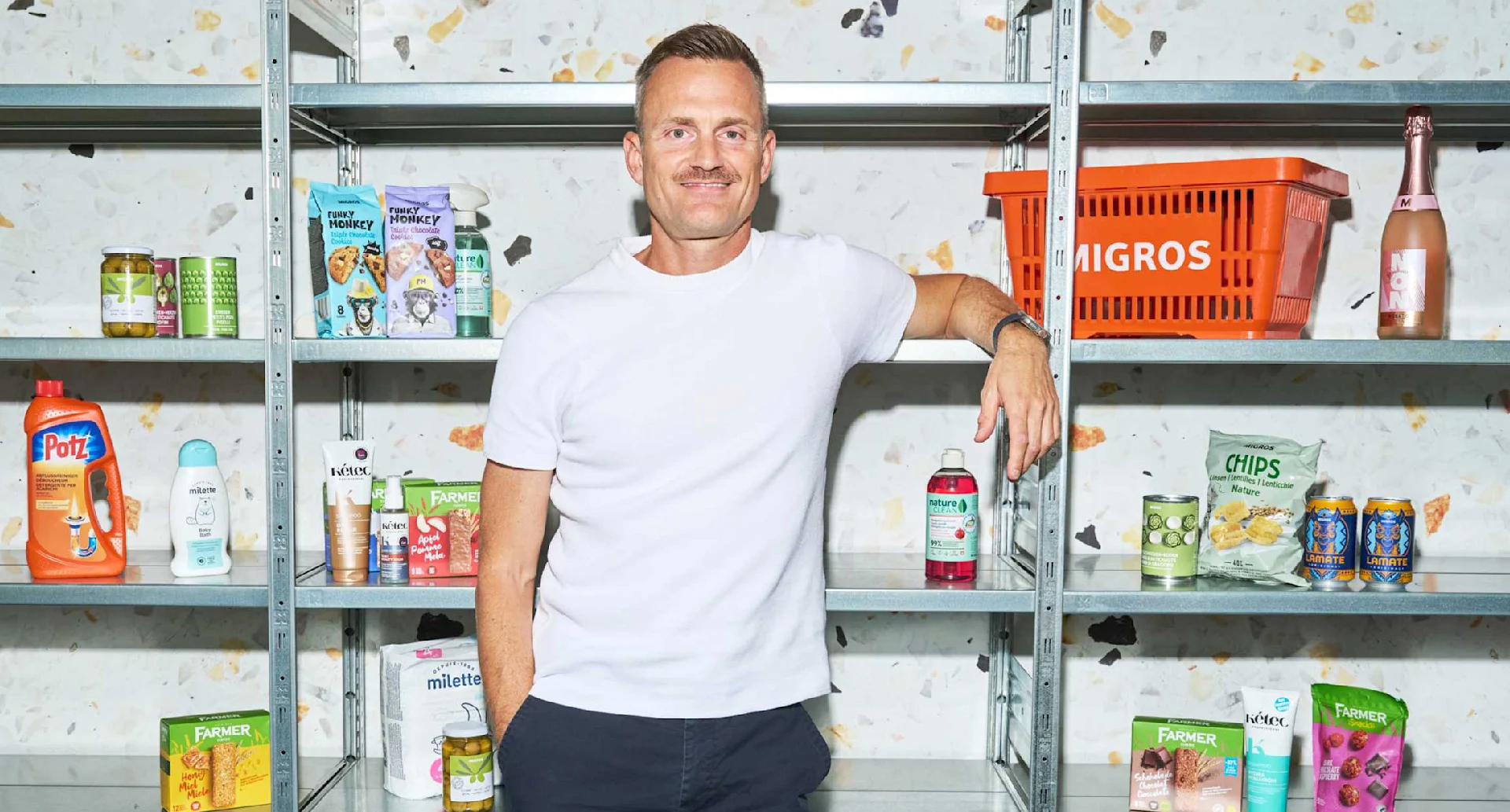 Migros Head of Marketing Rémy Müller in front of a shelf containing Migros own-brand products in the new design.