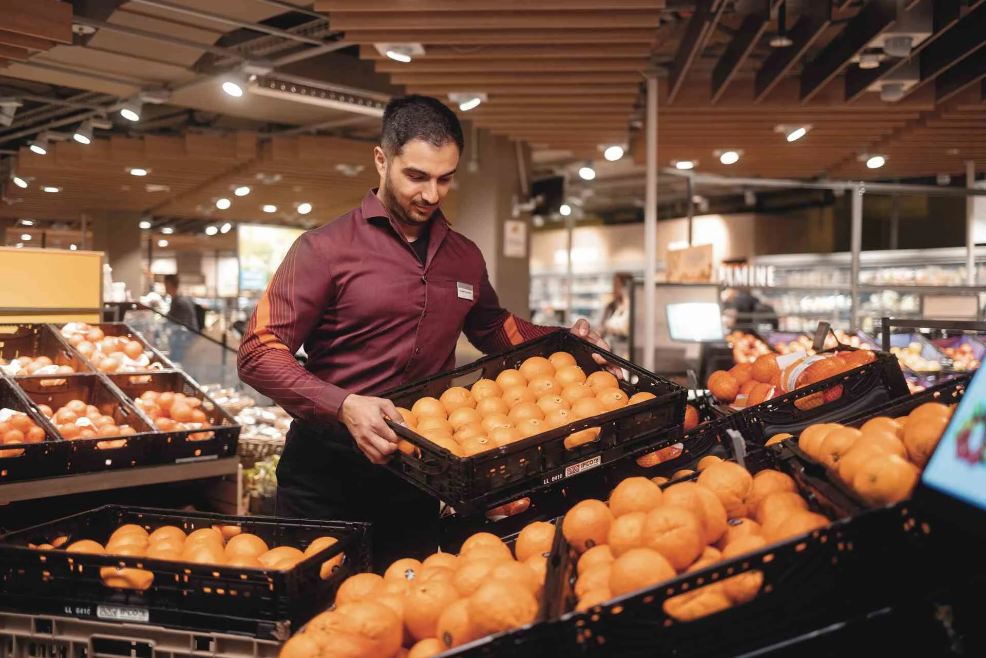 Un dipendente ricarica la frutta nel negozio.