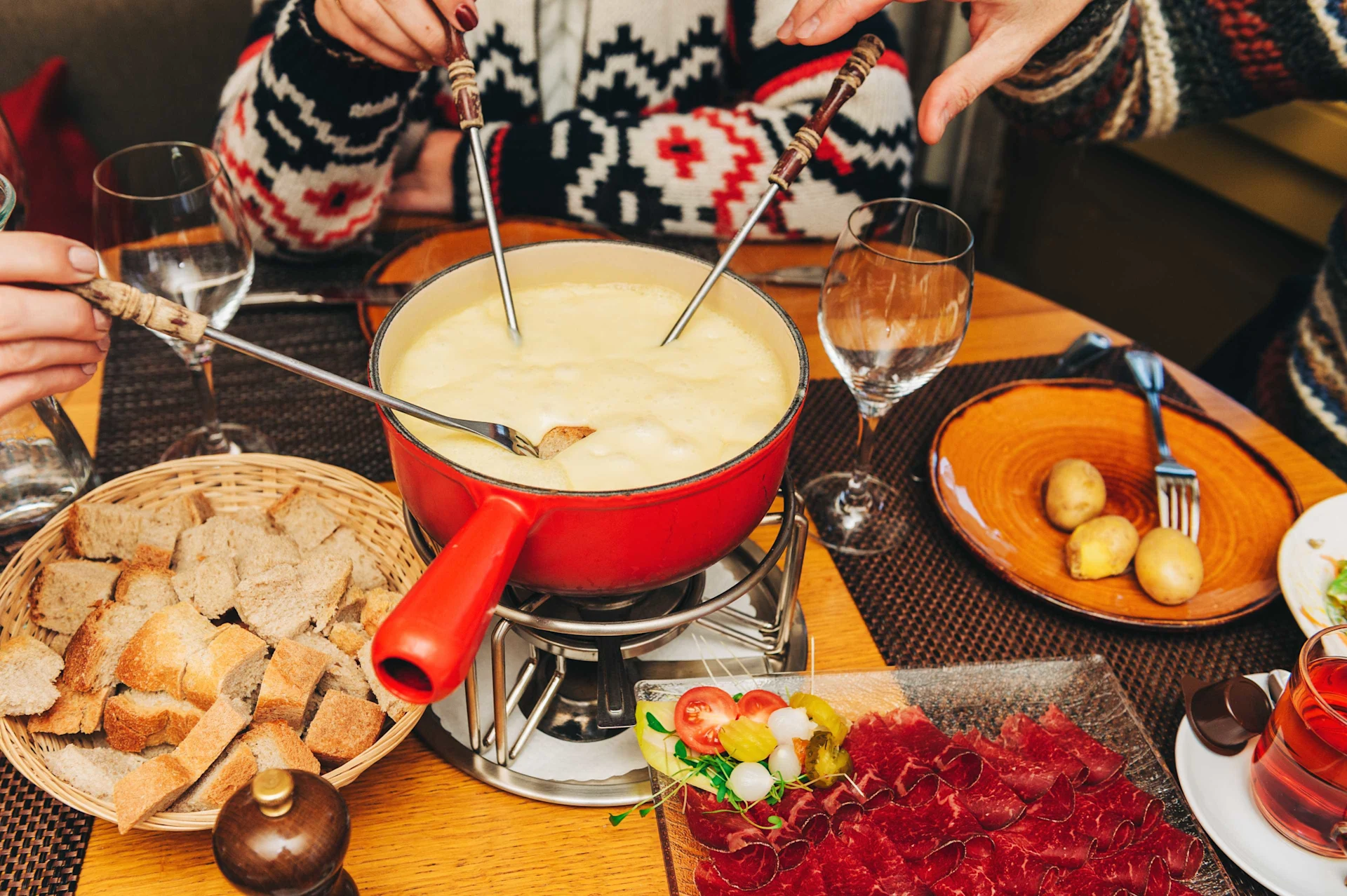 Mehrere Personen rühren mit der Gabel in einem Fondue.