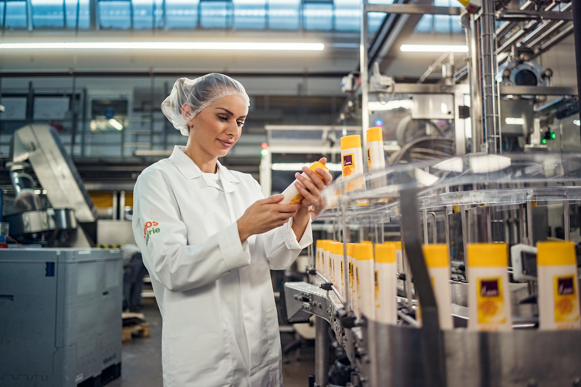 Una collaboratrice di Migros Industrie ritratta in fabbrica con in mano un flacone di gel doccia I am