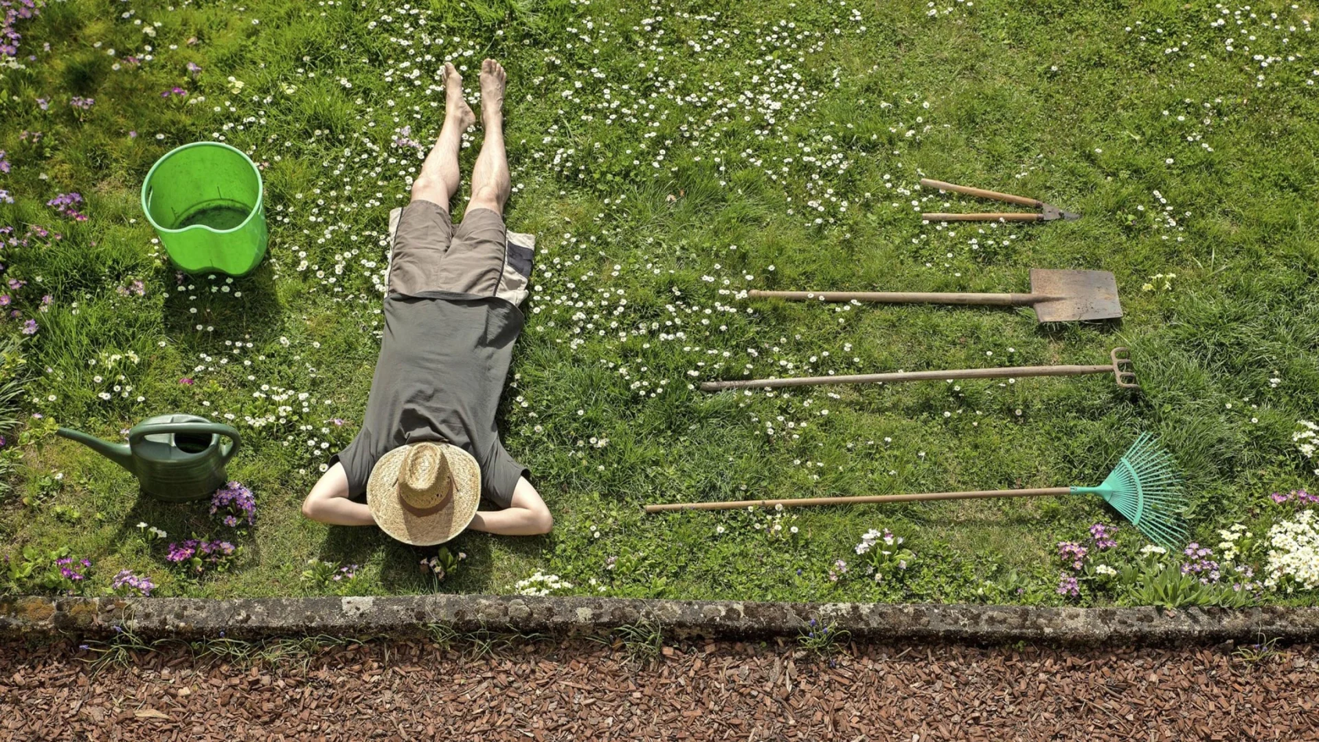 Ein Mann liegt auf dem Rasen und macht Pause von der Gartenarbeit