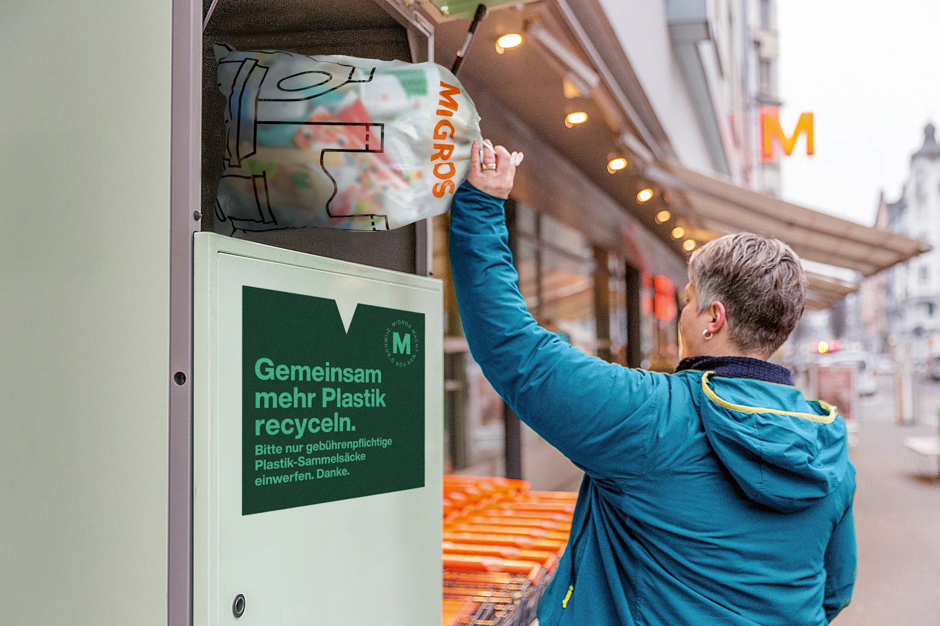 Eine Person wirft einen vollen Plastik-Sammelsack bei einer Rücknahmestelle ein.