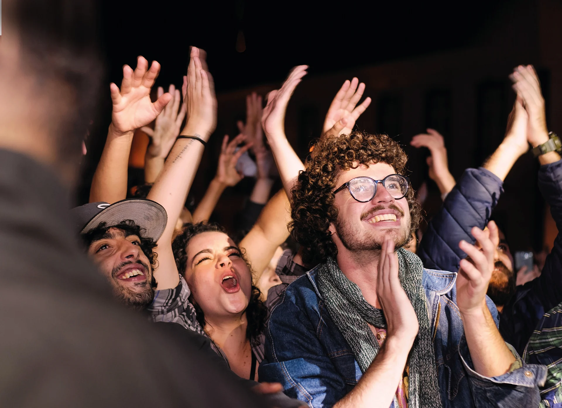 À un concert, un public nombreux sourit et applaudit.