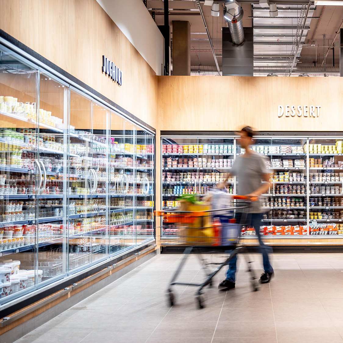 Un uomo con un carrello in un negozio Migros davanti allo scaffale refrigerato
