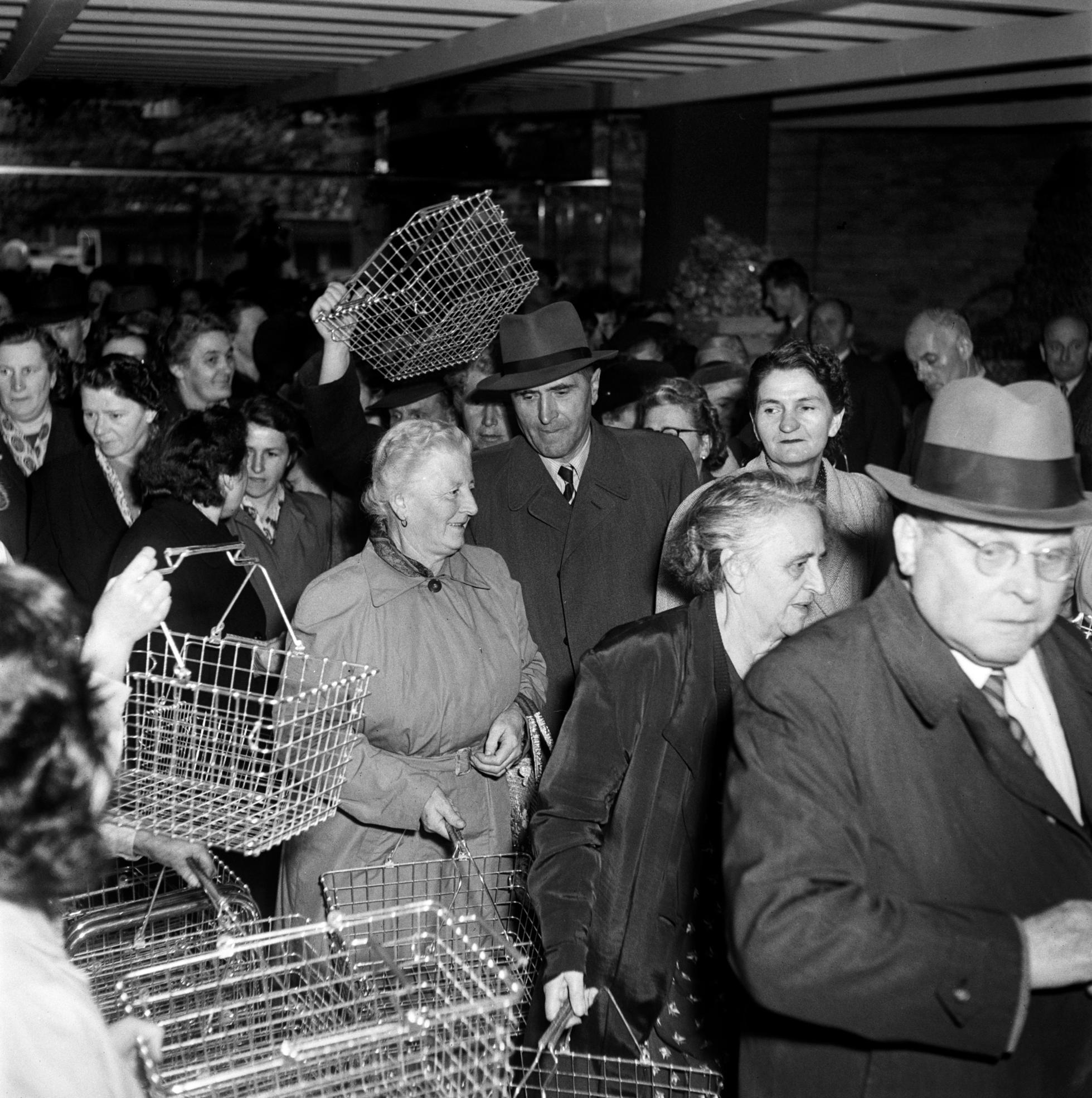 A black-and-white photograph of people queuing to get their shopping