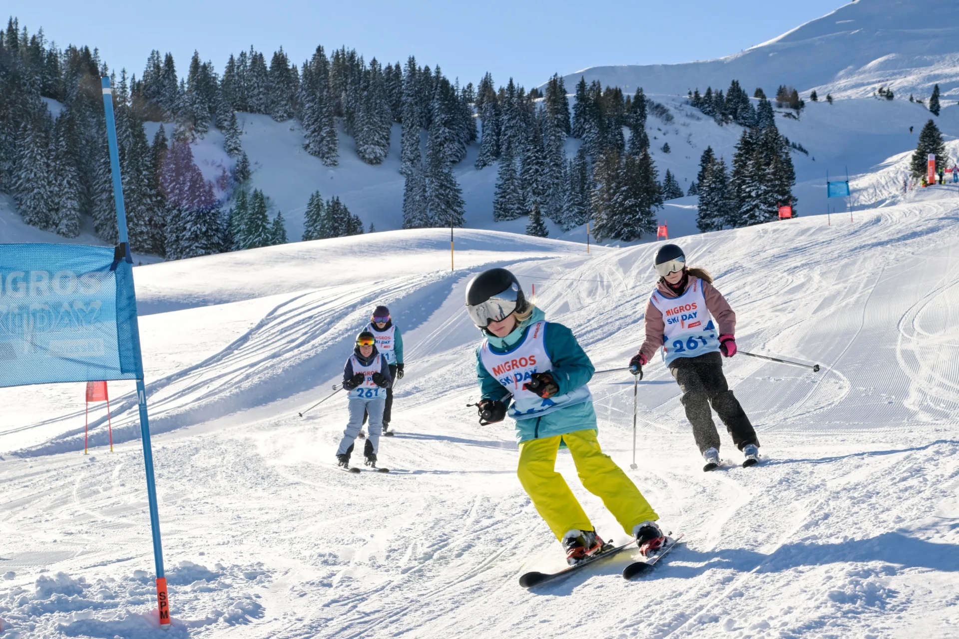 Family skiing down a slope during Migros Ski Day.
