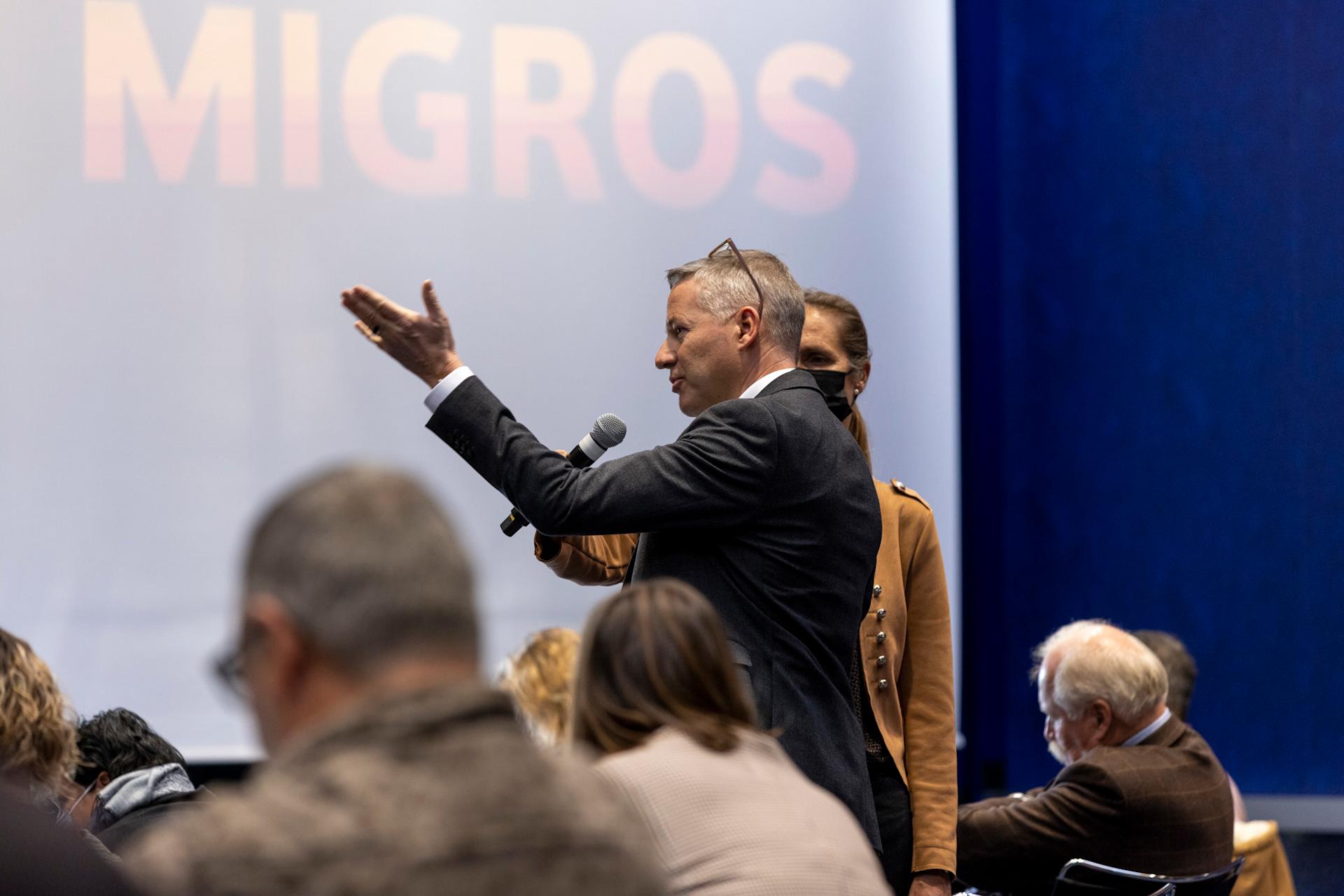 A gentleman is holding a microphone, speaking before the Assembly of Delegates