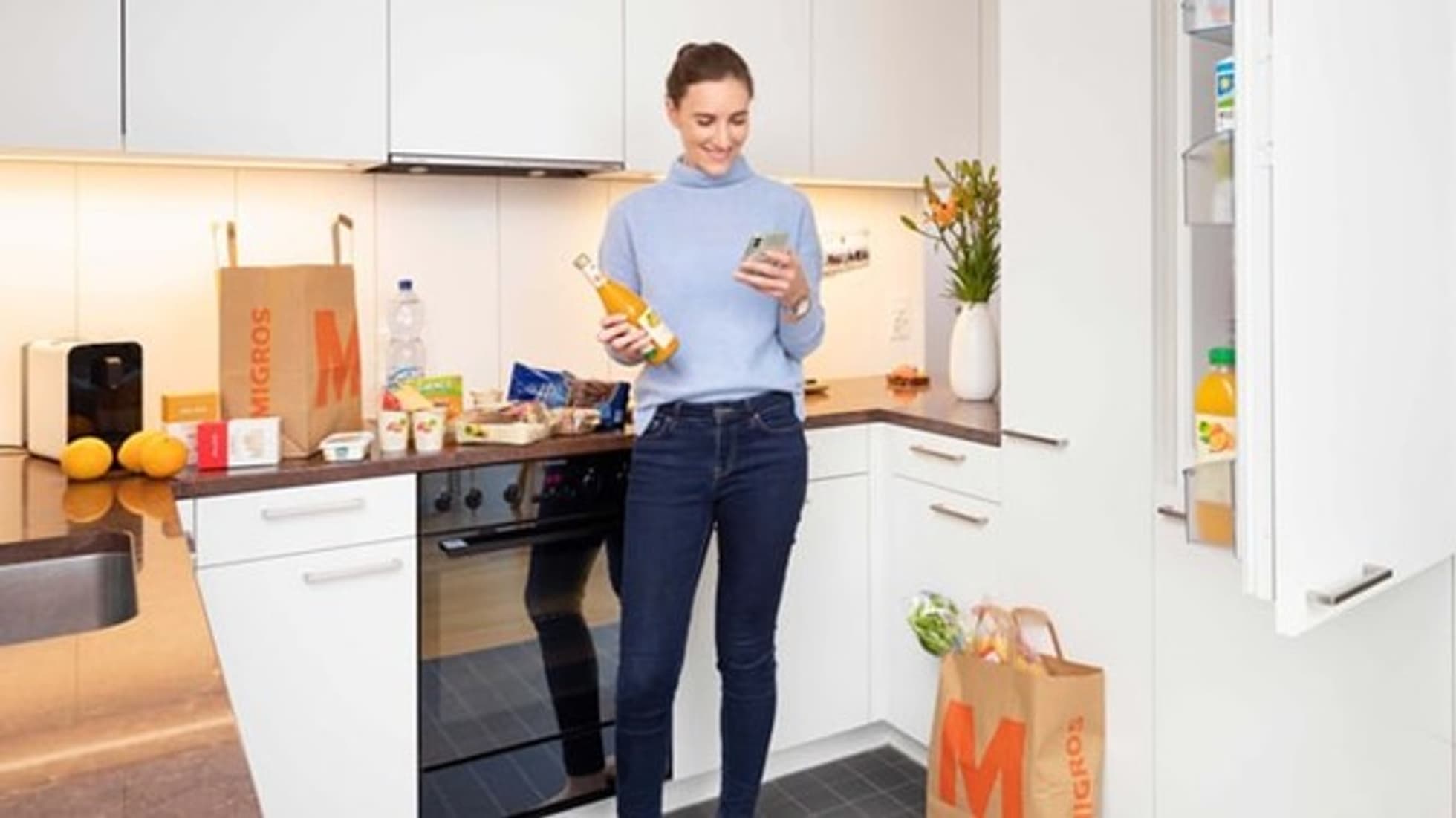 Eine Frau steht in der Küche und packt Einkäufe in den Kühlschrank